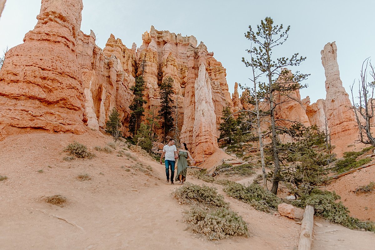  Man and woman recently engaged running through Bryce Canyon red rocks by Lucy Bouman 