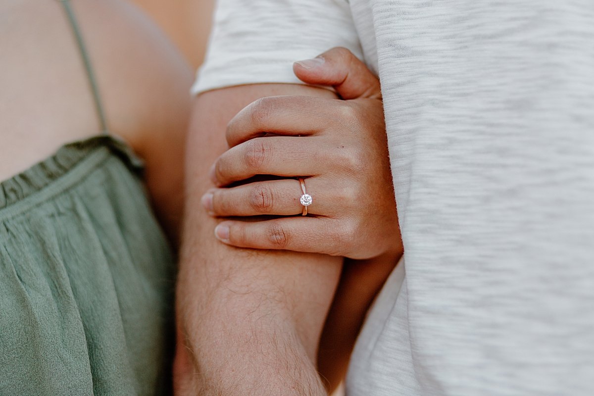  Women's arm wrapped around fiancés bicep showing off diamond engagement ring with Utah couples photographer 