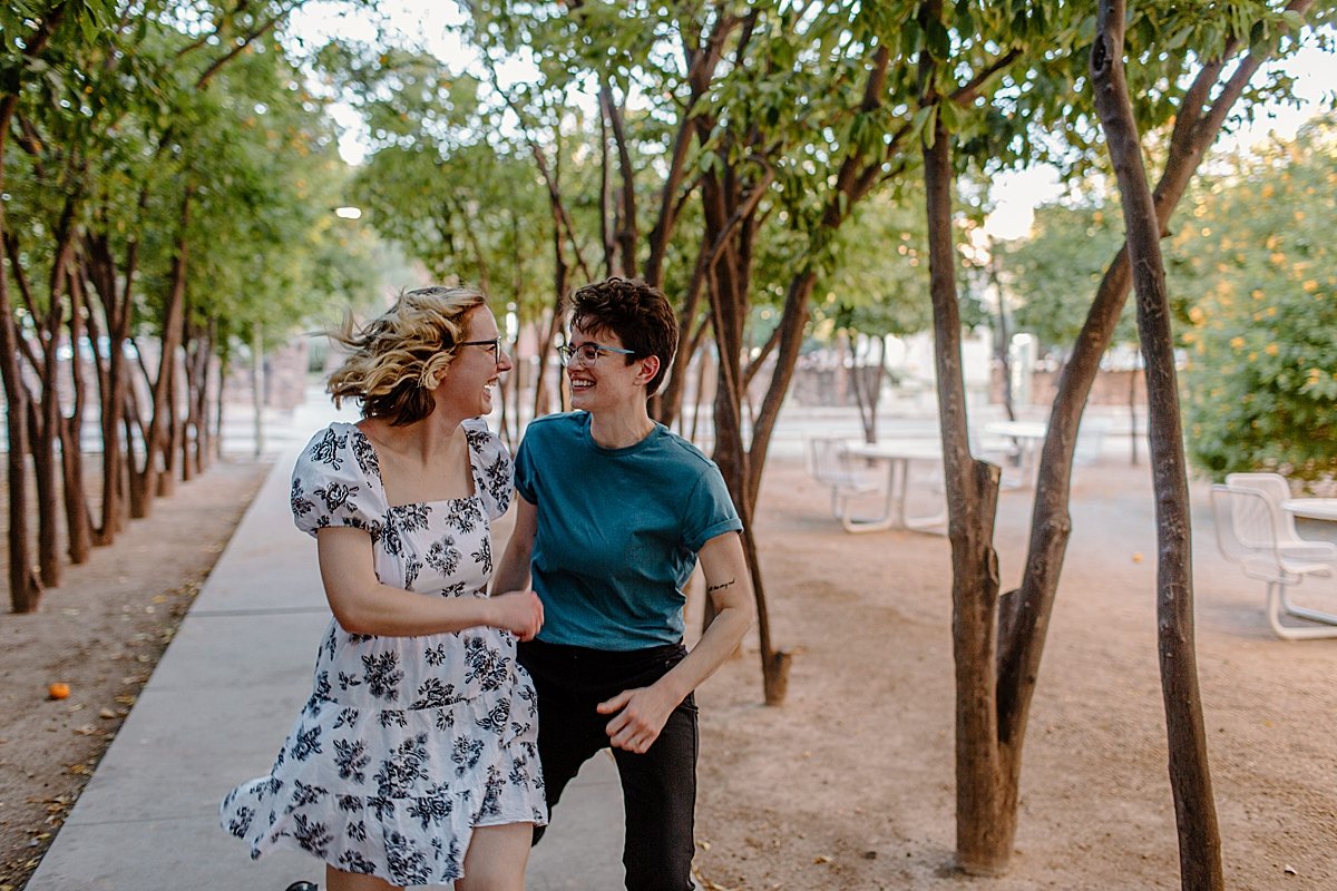  Couple running through the streets of Arizona campus for engagement session at Windy point 