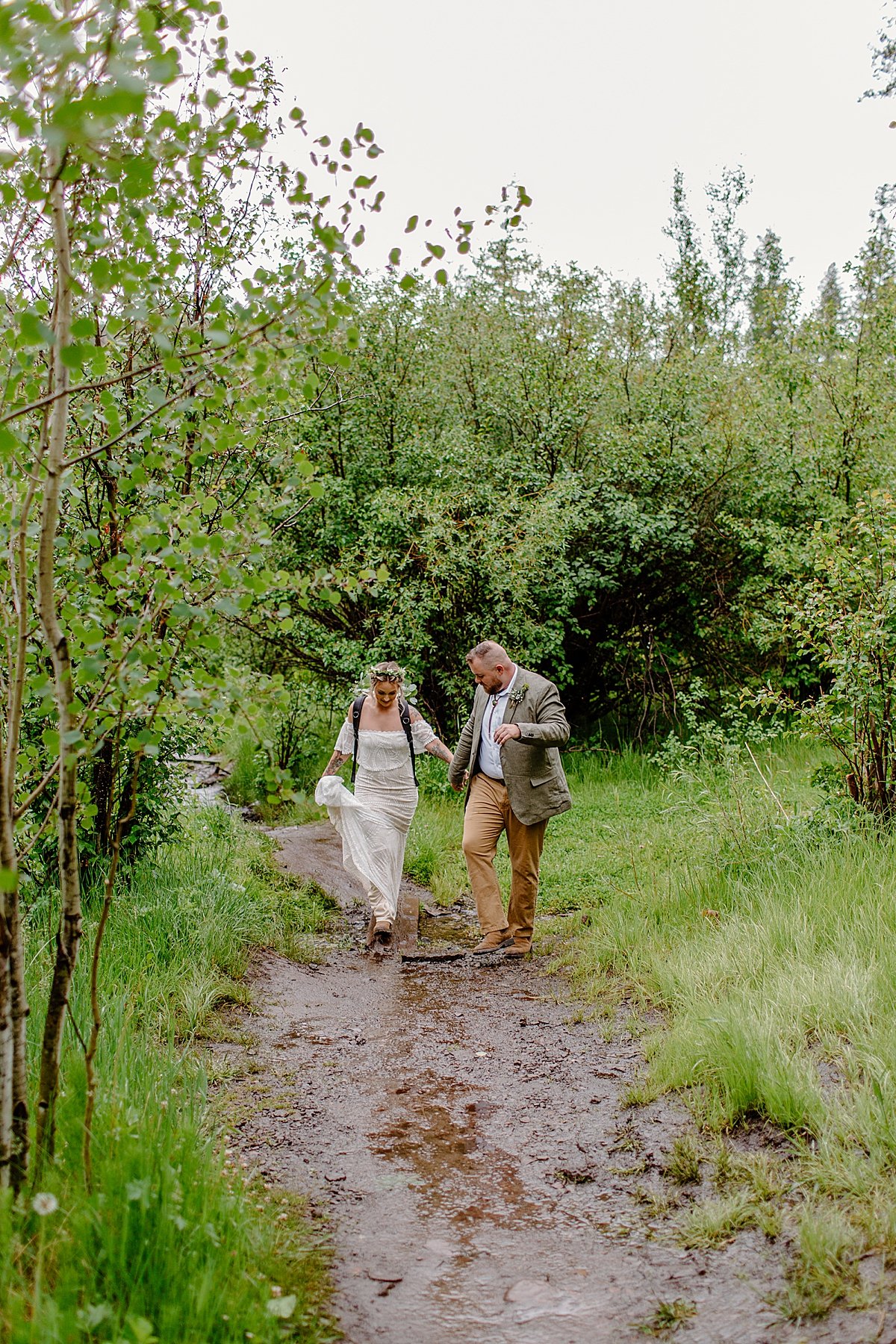  Walking through mud towards ceremony elopement location in wedding dress attire  by Lucy Bouman 