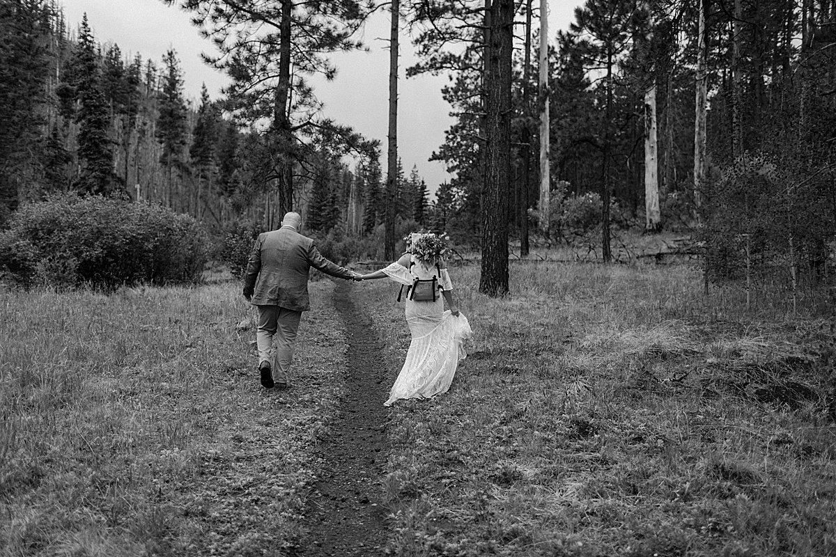  Black and white portrait of bride and groom holding hands on walking path  by Lucy Bouman 