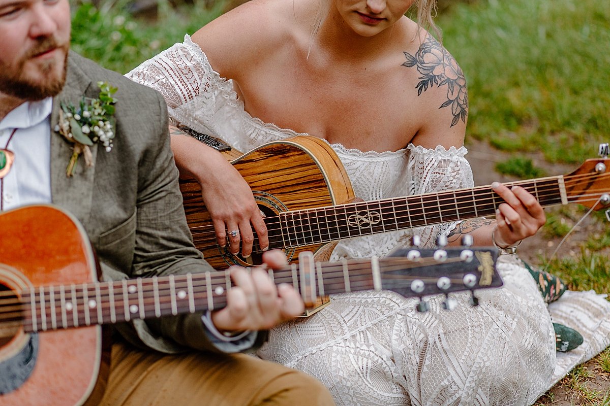  Newly married couple sitting on picnic blanket Play guitar by Arizona adventure elopement photographer 