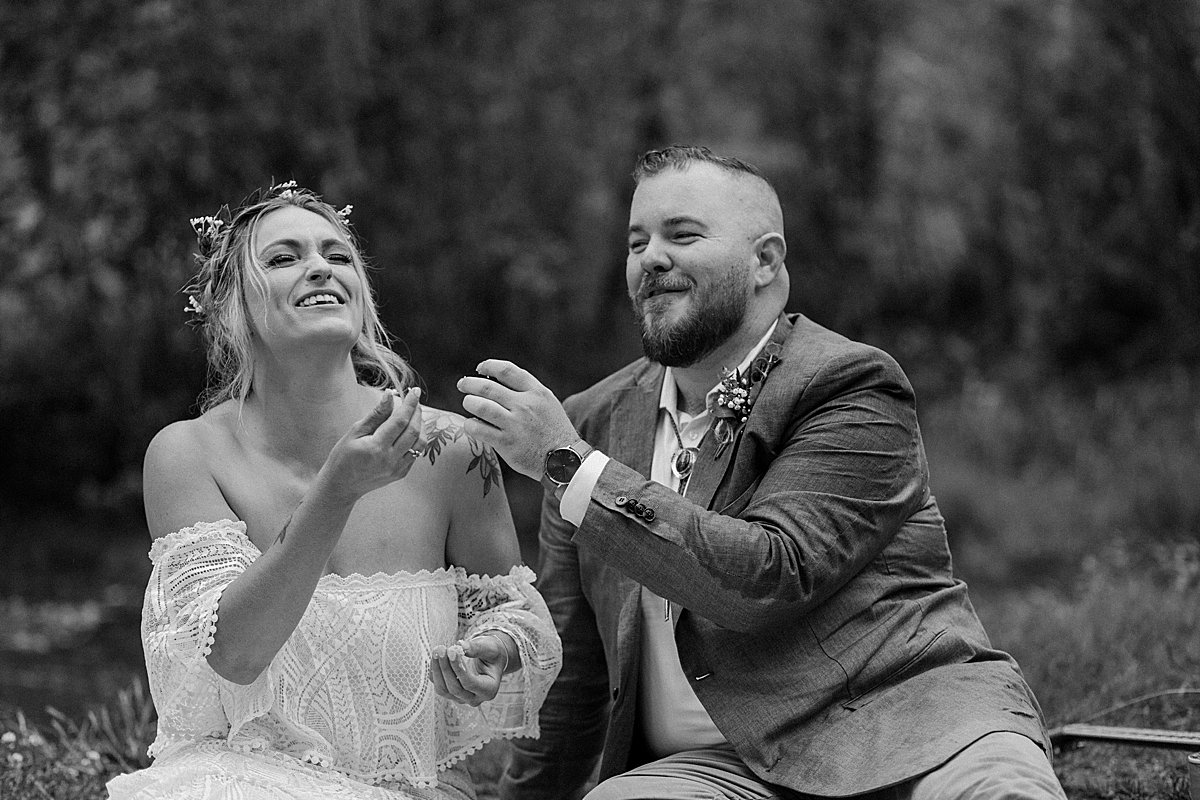  Bride and groom cut wedding cake on picnic blanket and take a bite by Arizona adventure elopement photographer 