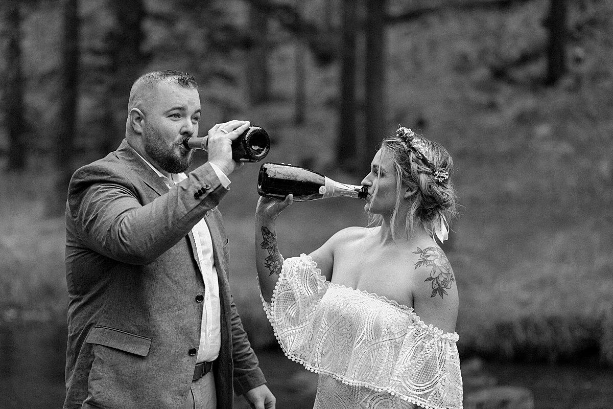  Black and white portrait of married couple drinking from bottles of champagne by Arizona adventure elopement photographer 