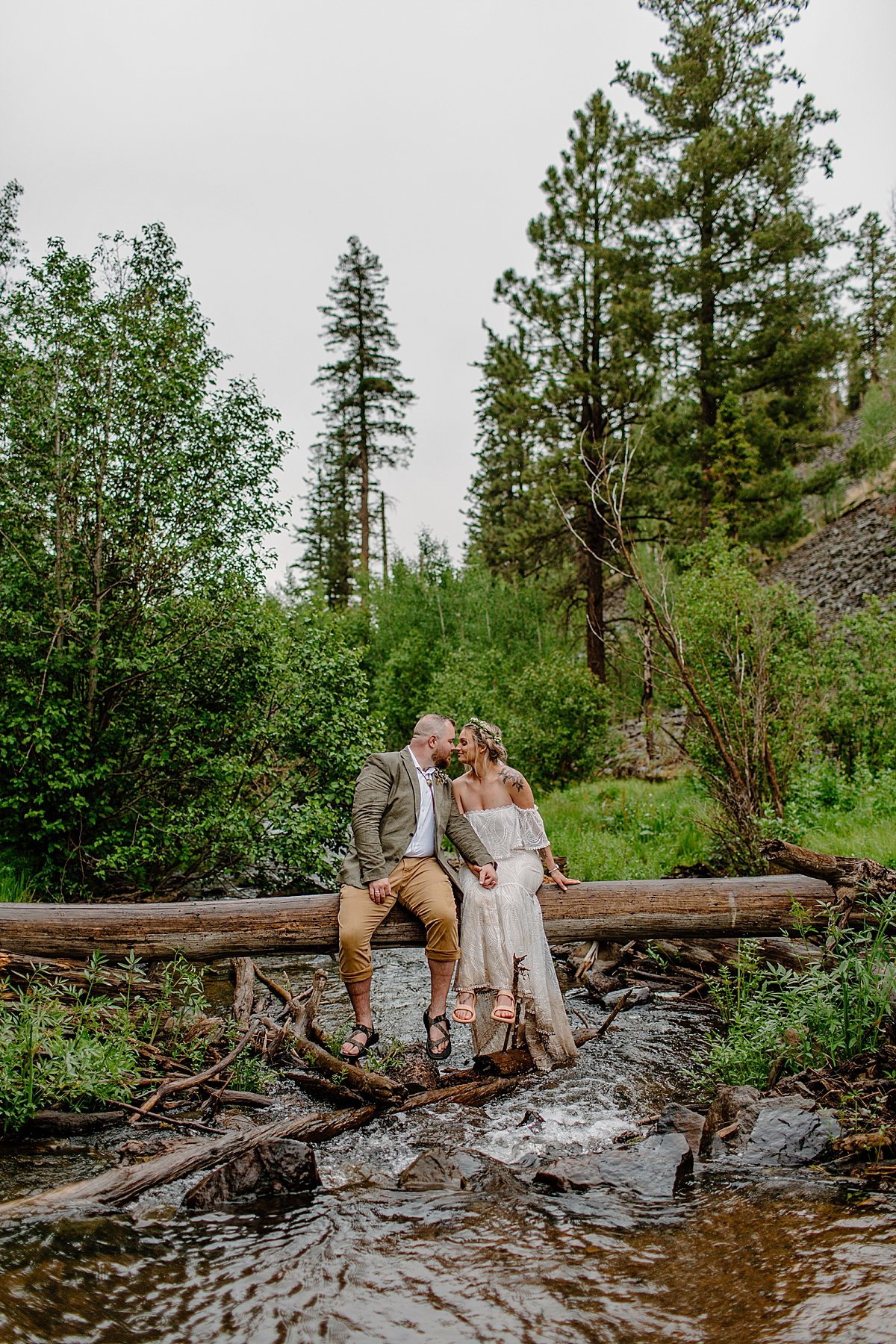  Newly married couple sitting on log overlooking river after ceremony for Greer elopement 