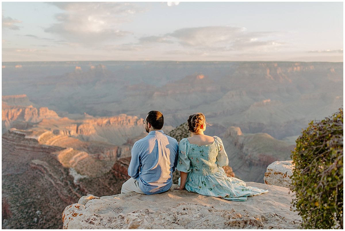  Couple sits together on overlook at Grand Canyon Engagement Session 
