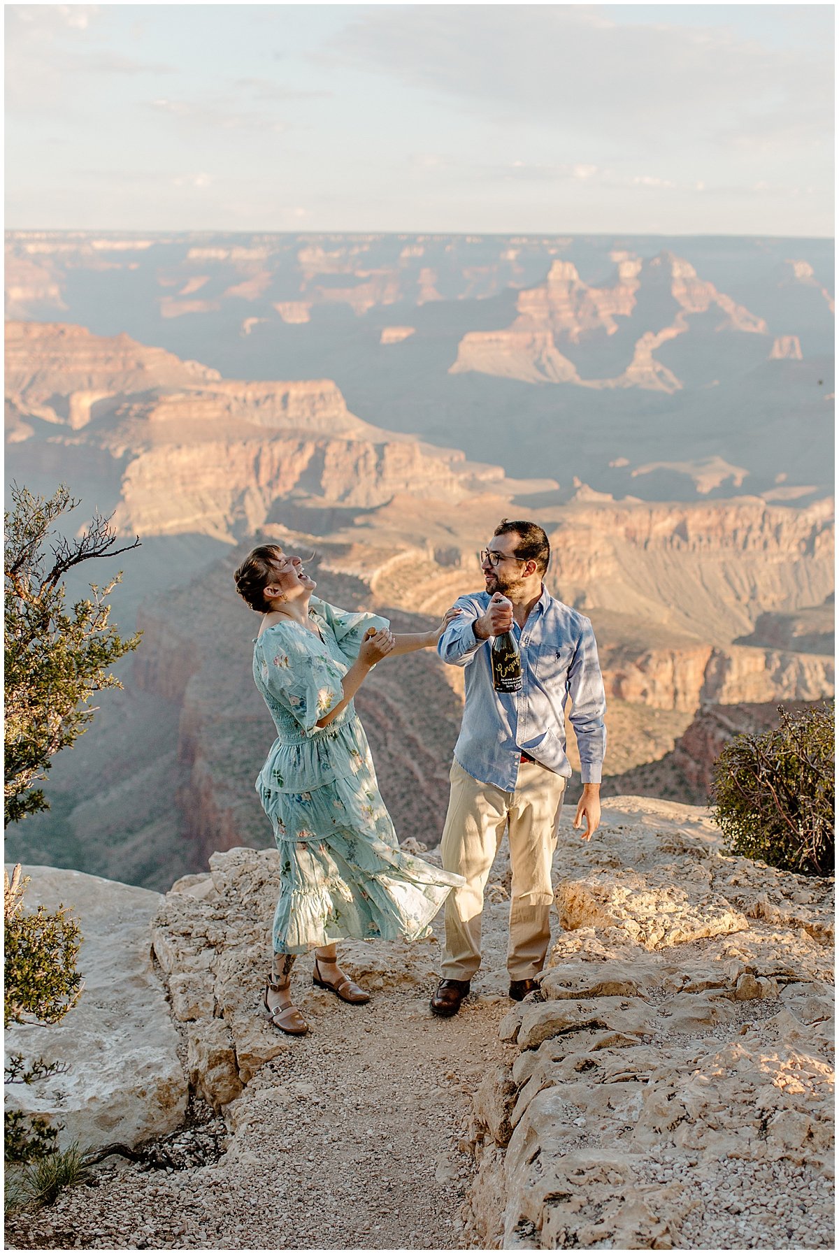  Woman throws head back laughing as man pops champagne for Lucy Bouman Photography 