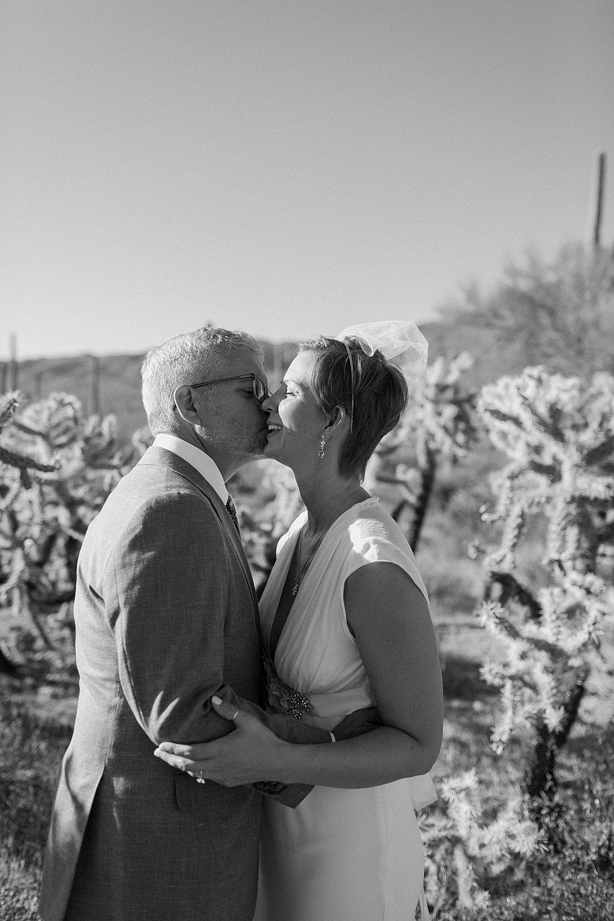  Husband and wife kiss in the desert at Saguaro National Park 