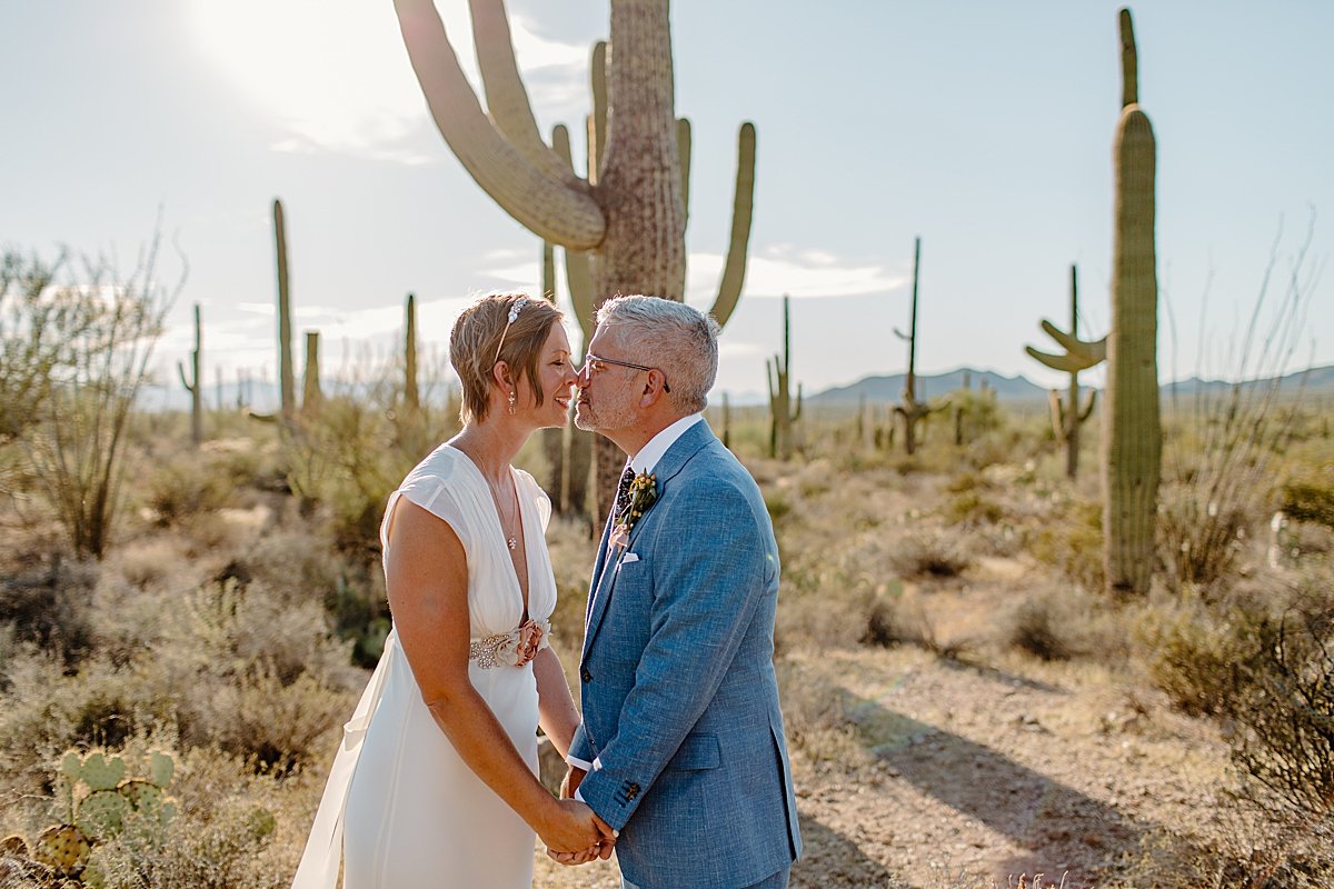  Woman kissing her new husband in front of cactus  by Lucy Bouman Photography 
