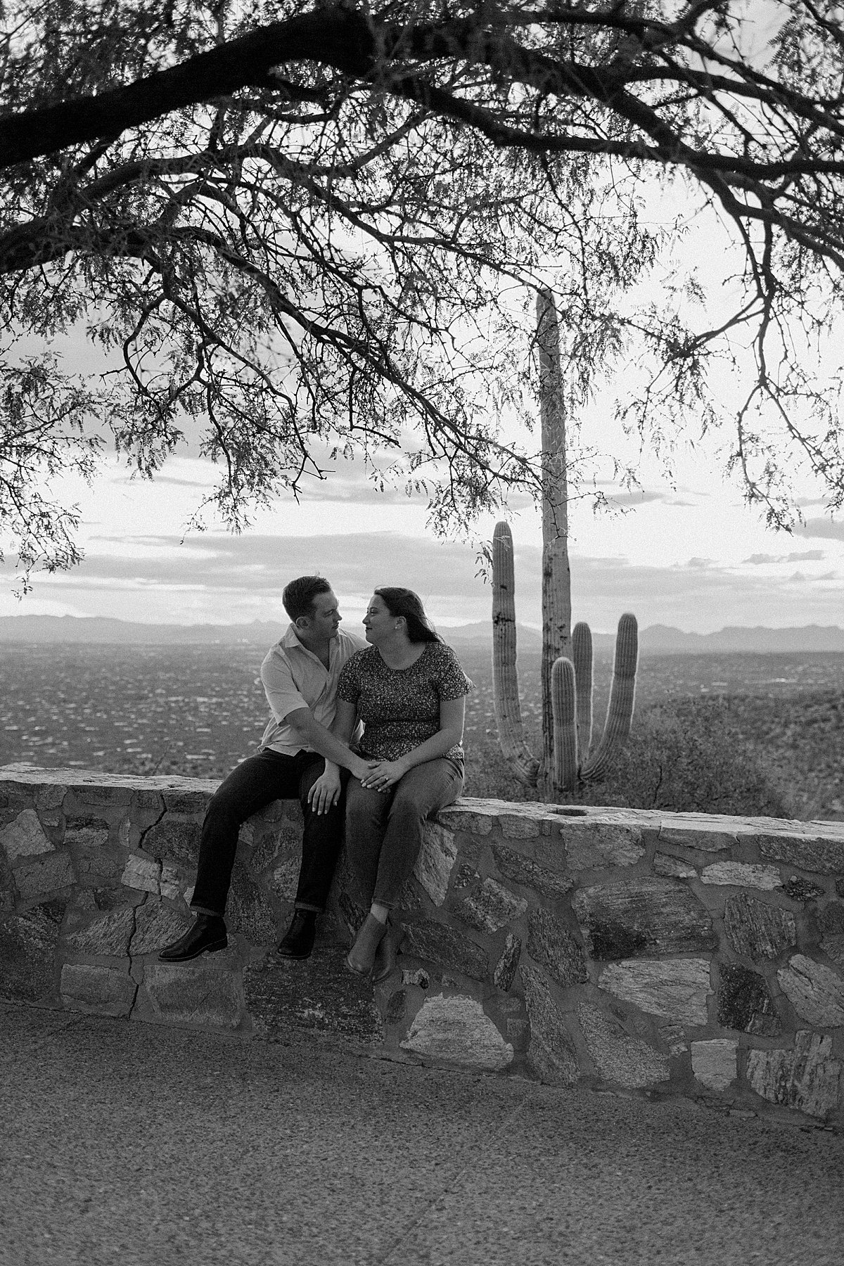  fiances sit together on wall for Arizona engagement photographer 