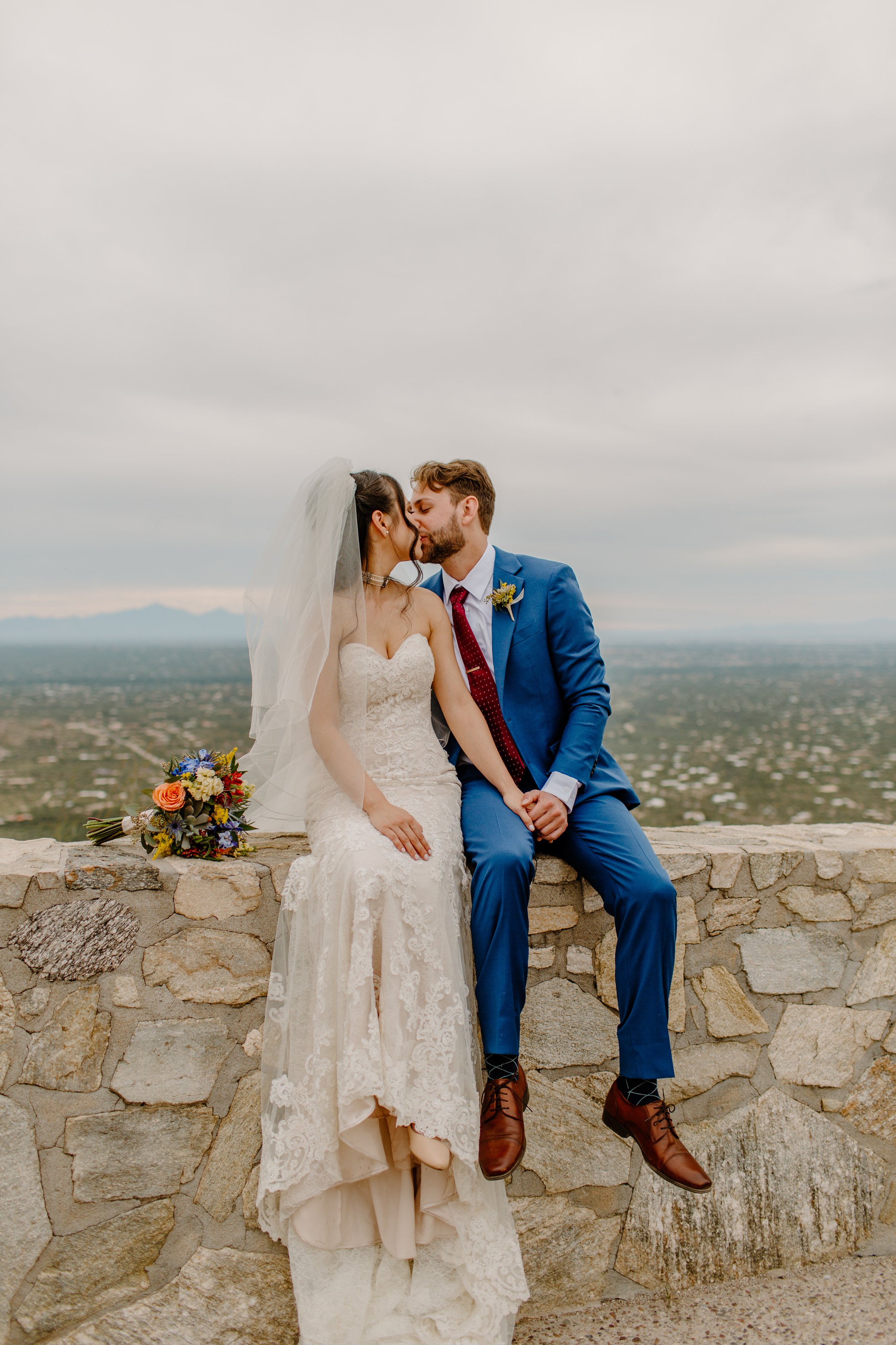  married couple sitting on the ledge of park wall by Arizona elopement photographer  