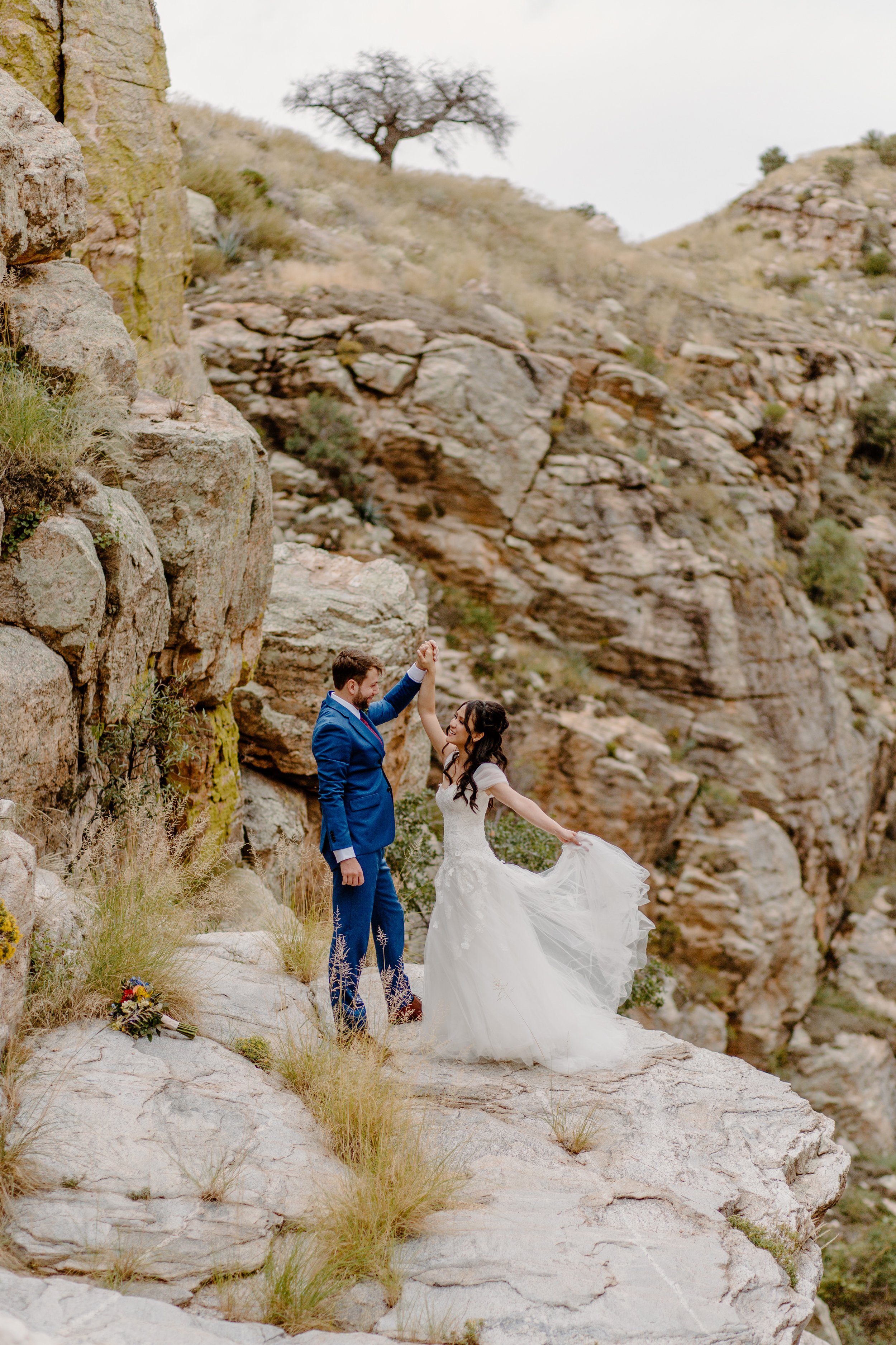  bride holding train standing on the rocks of desert canyon by Lucy bouman photo  
