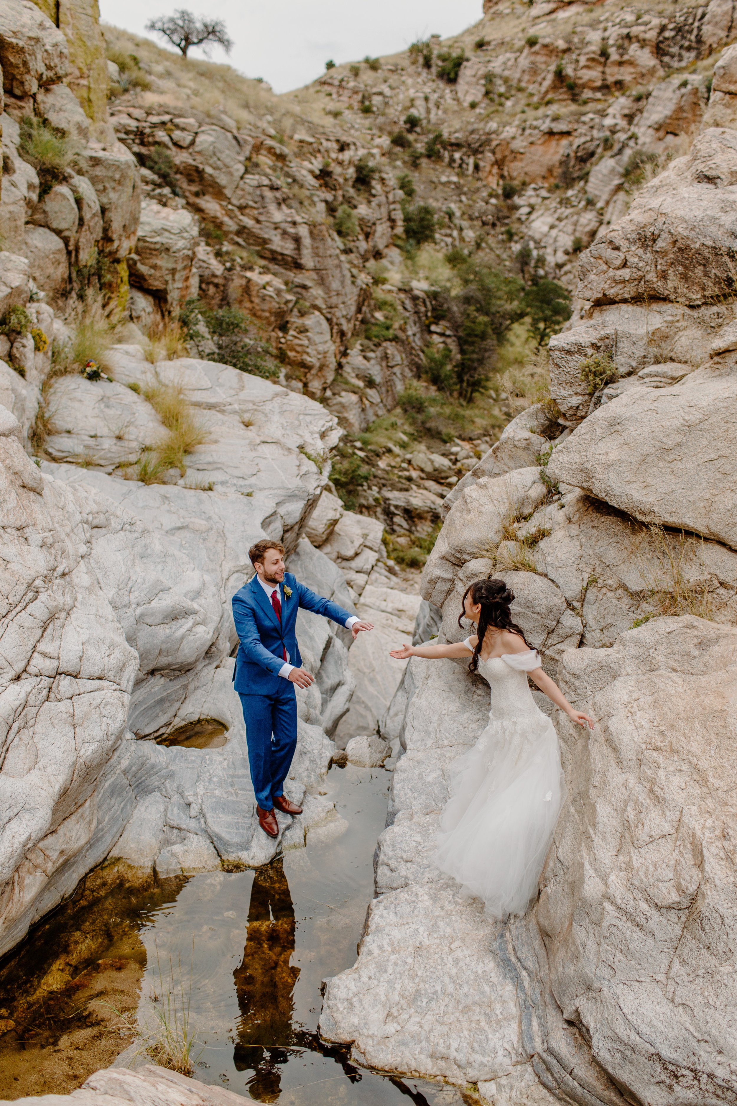  bride and groom standing on boulders in Arizona on rock climbing session 