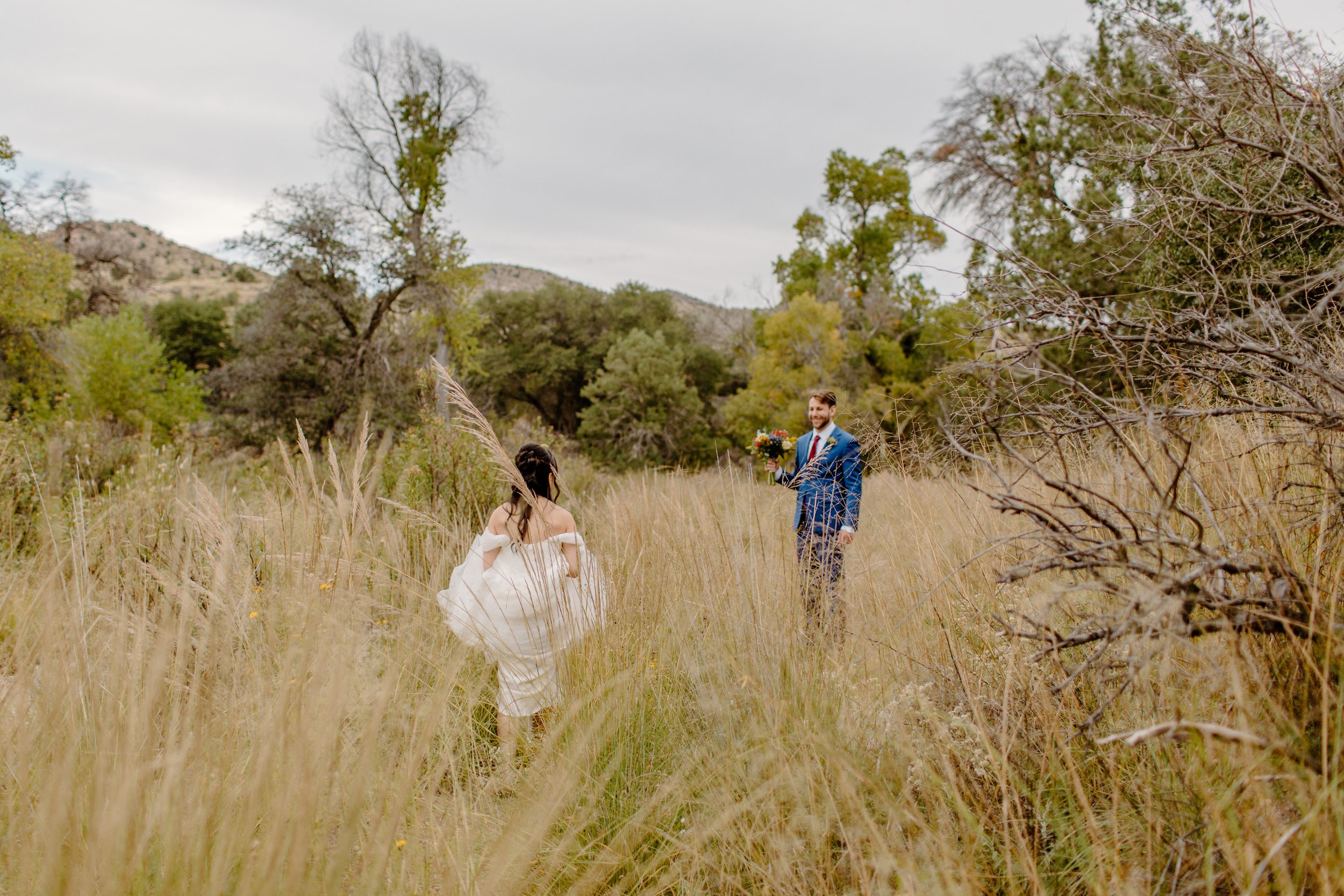  man and woman walking through tall grass in wedding apparel by Lucy bouman photo  