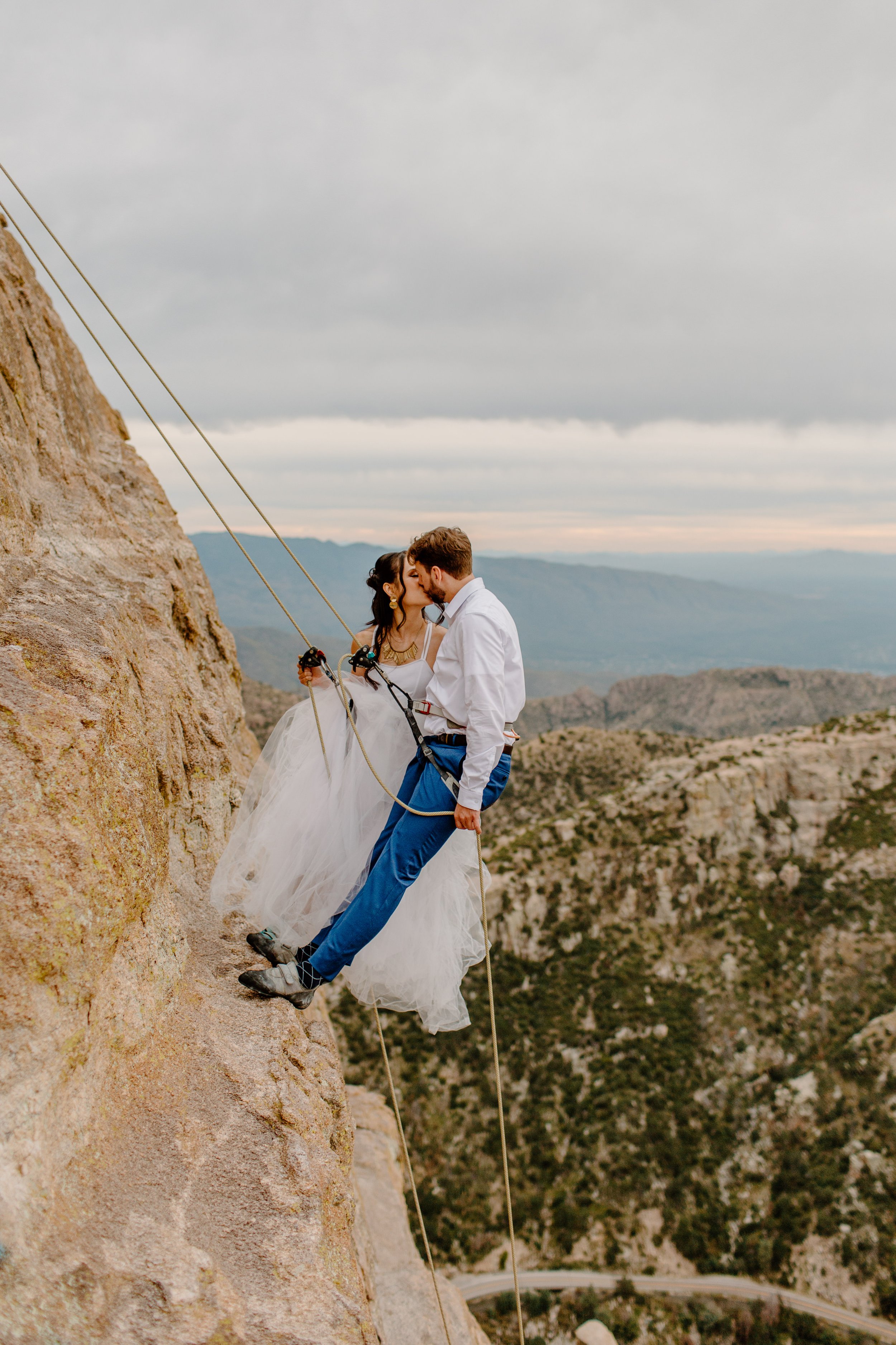  married couple on the side of a cliff with ropes for rock climbing session 