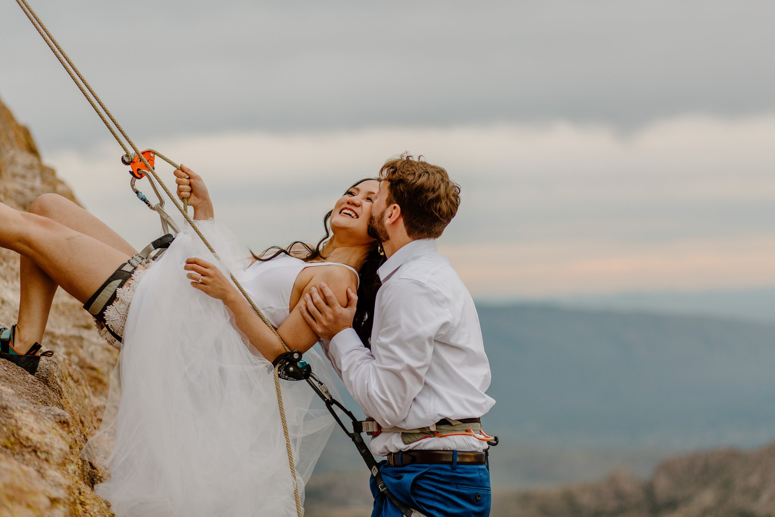  couple climbing up a rock wall on wedding day by Arizona elopement photographer  