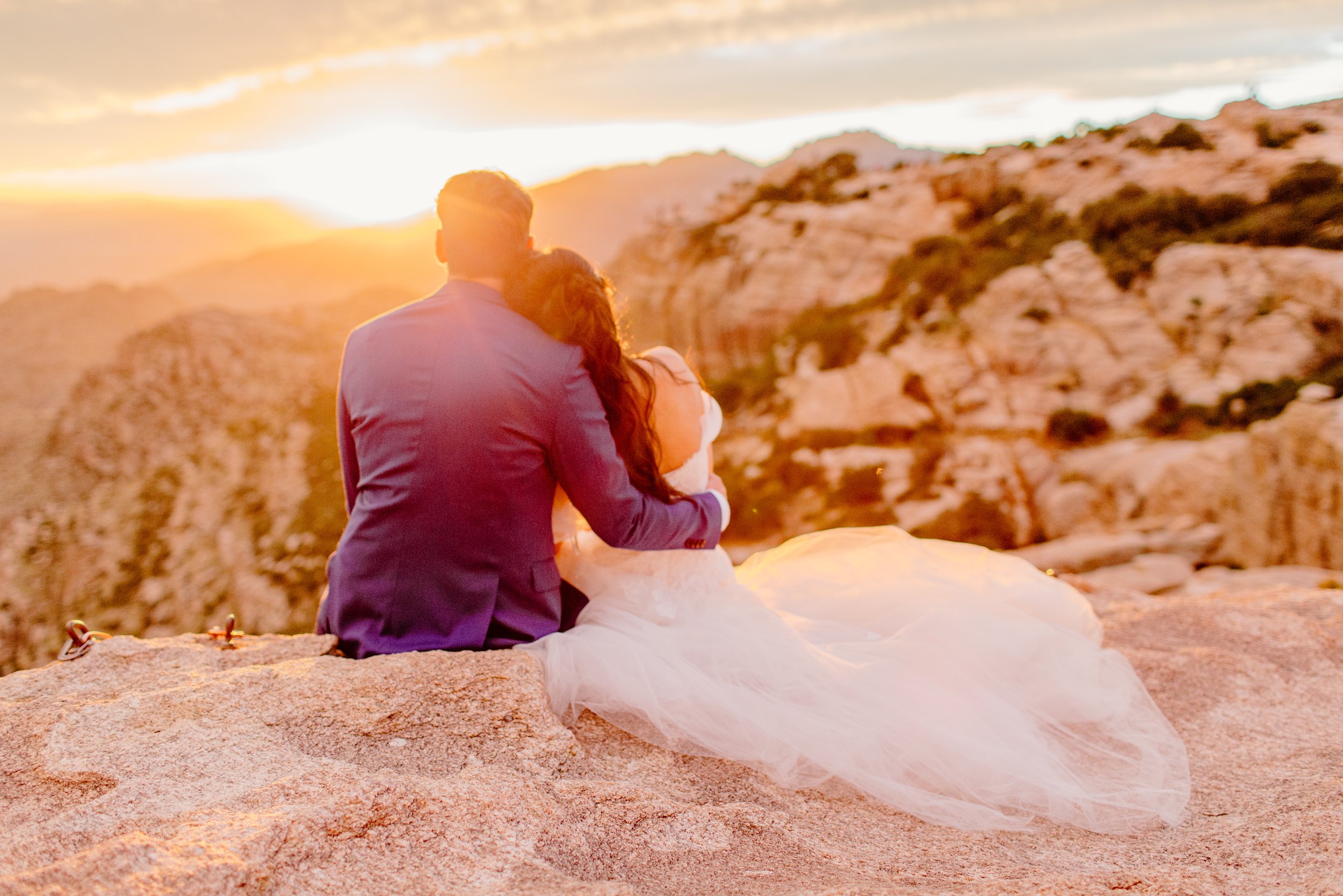  couple wearing dress and suit sitting on the canyon at sunset for rock climbing session 