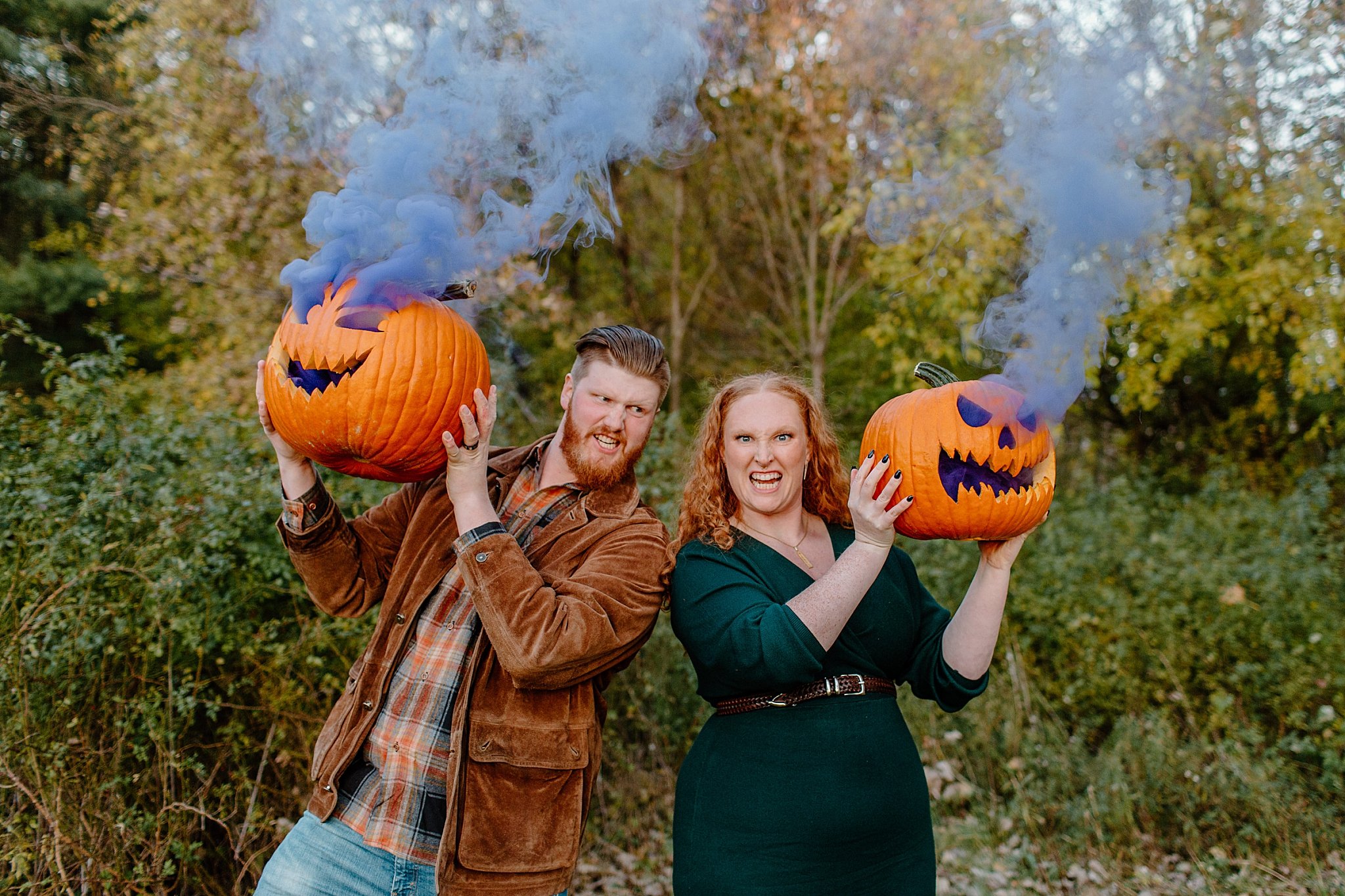  Man and woman peek out from behind carved pumpkins for Halloween engagement session 