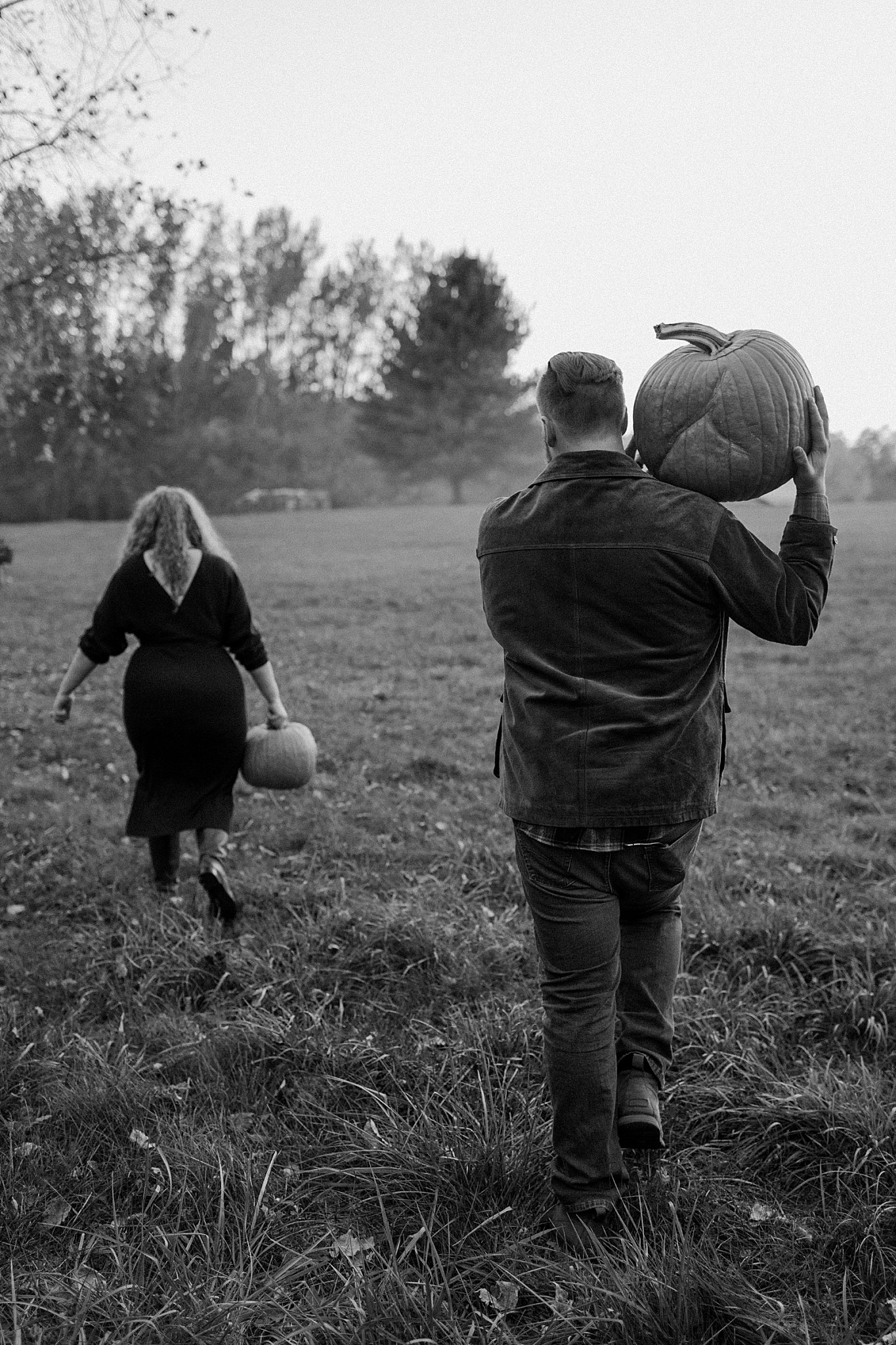  Two people walk away in field carrying pumpkins for Lucy B Photography 