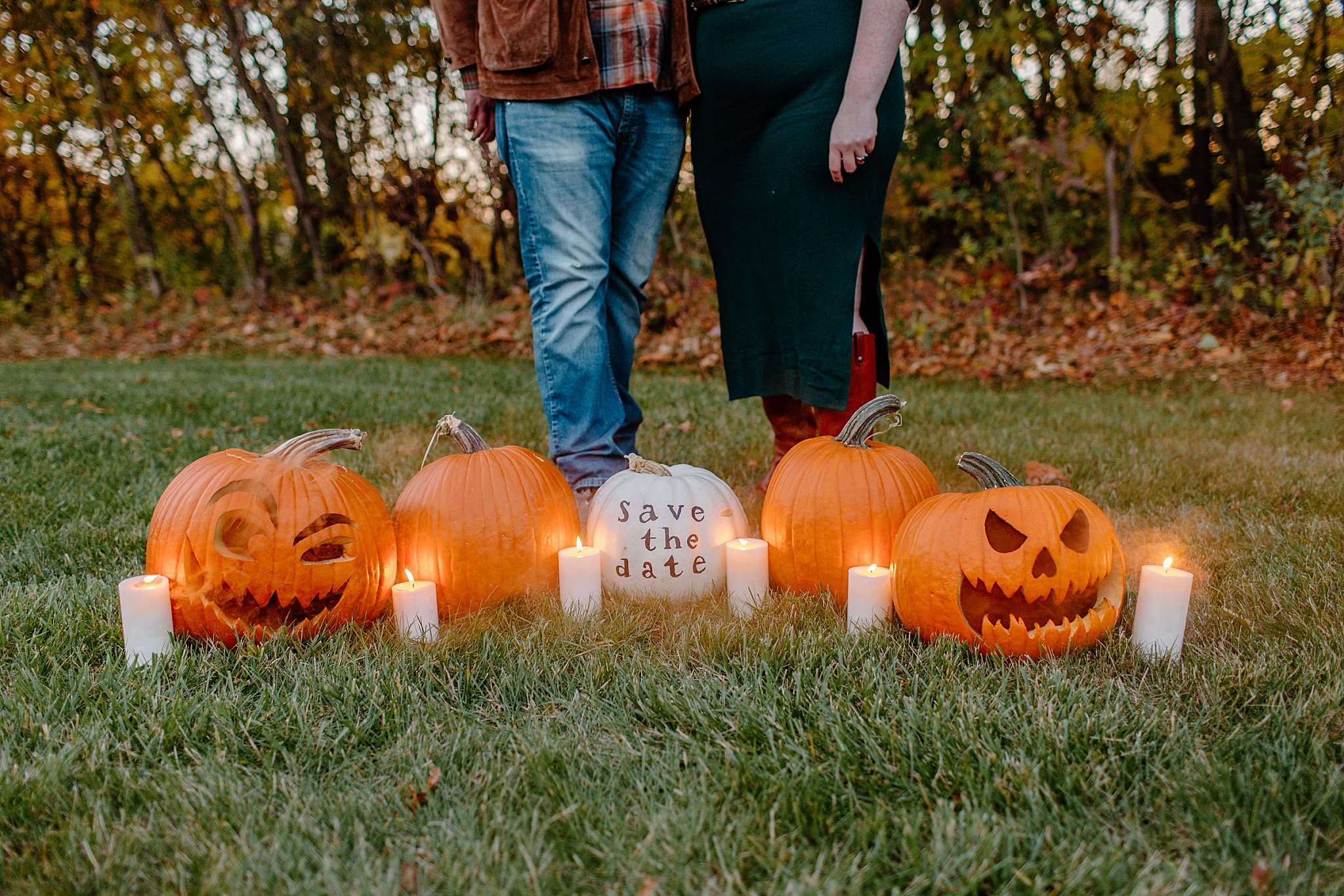  pumpkins and candles are arranged on grass with people standing behind by Lucy B Photography 