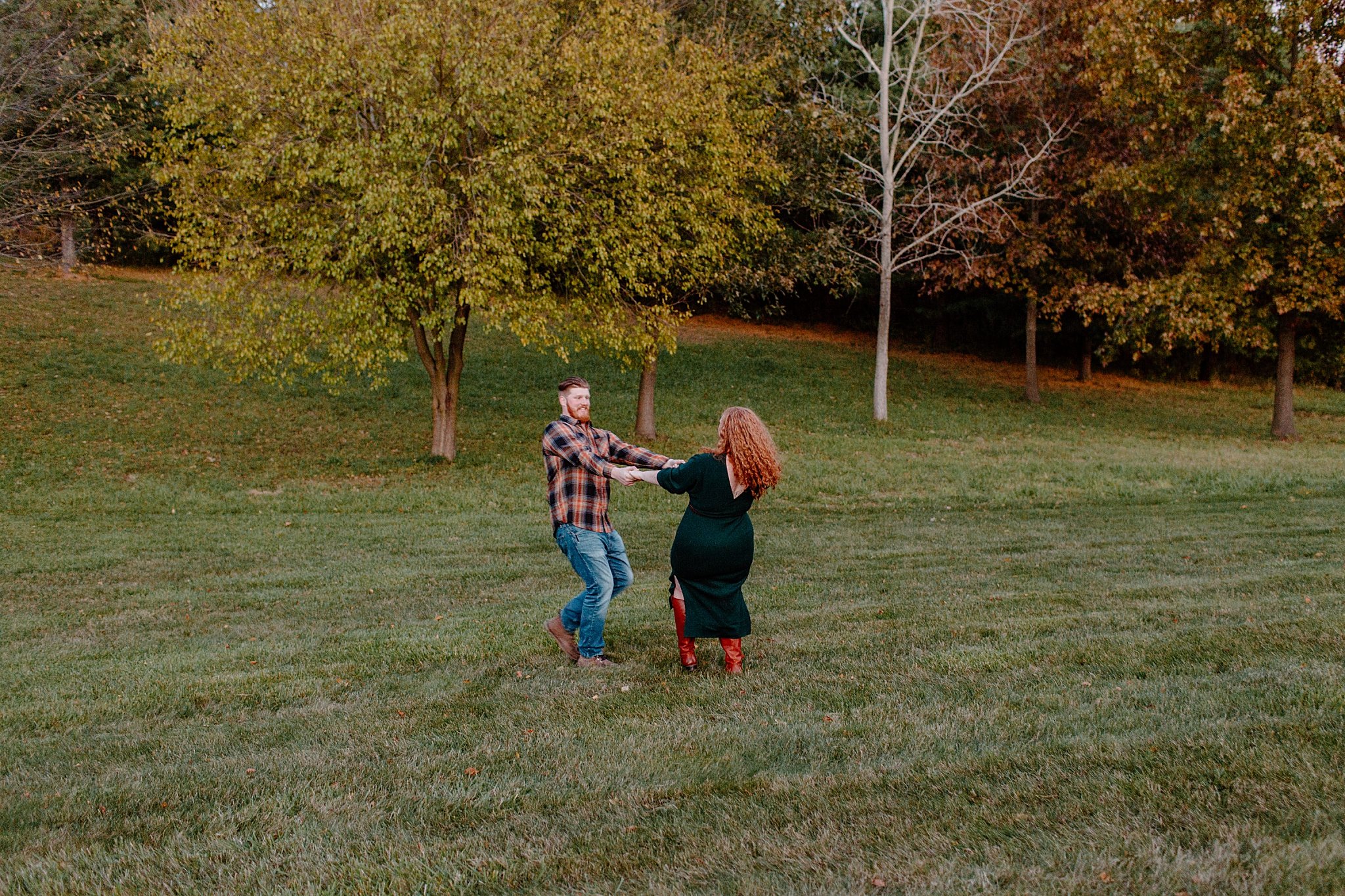  Man and woman dance in open field at Halloween engagement session 