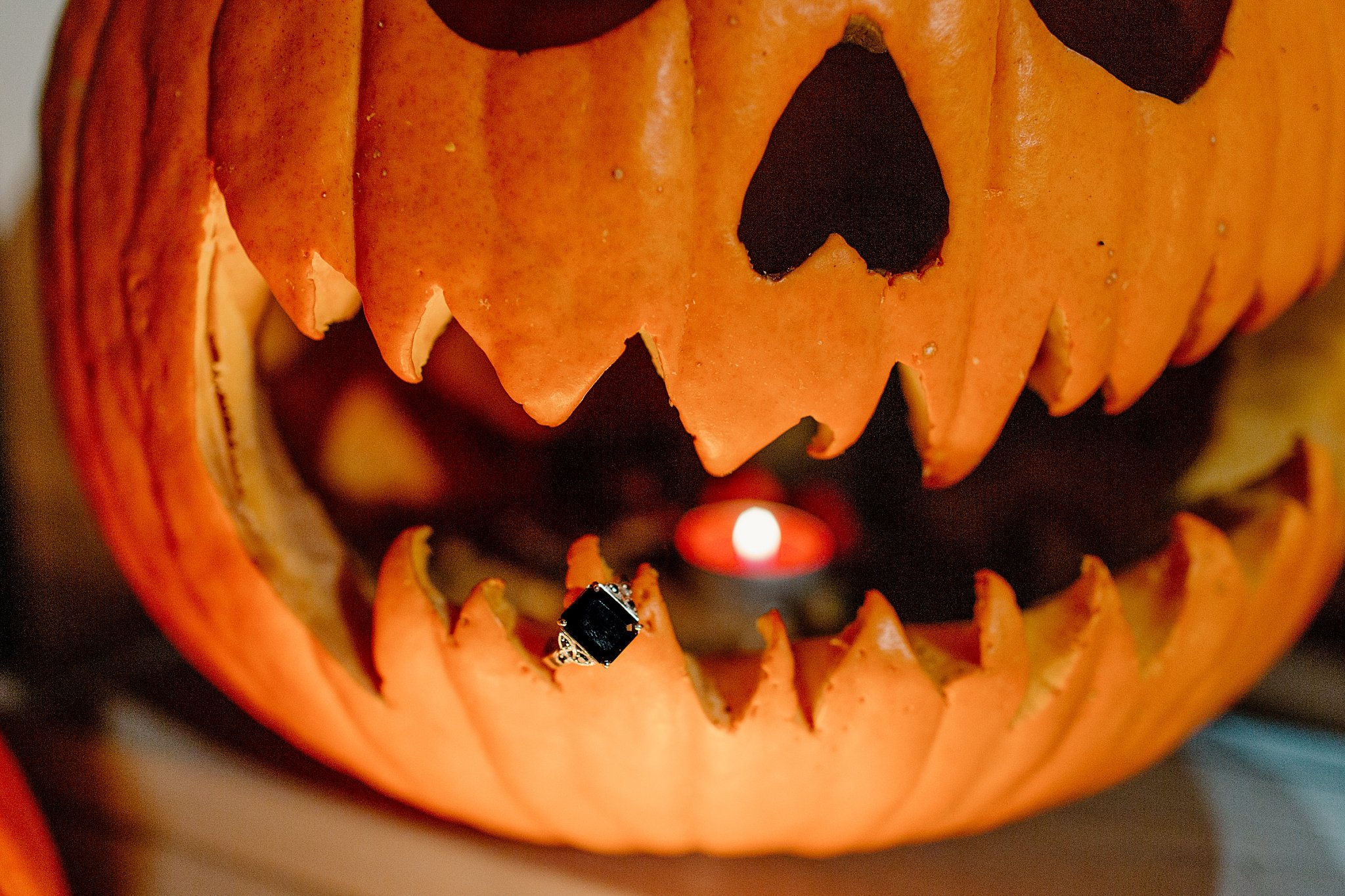  Ring hangs off tooth of jack-o-lantern at Halloween engagement session 