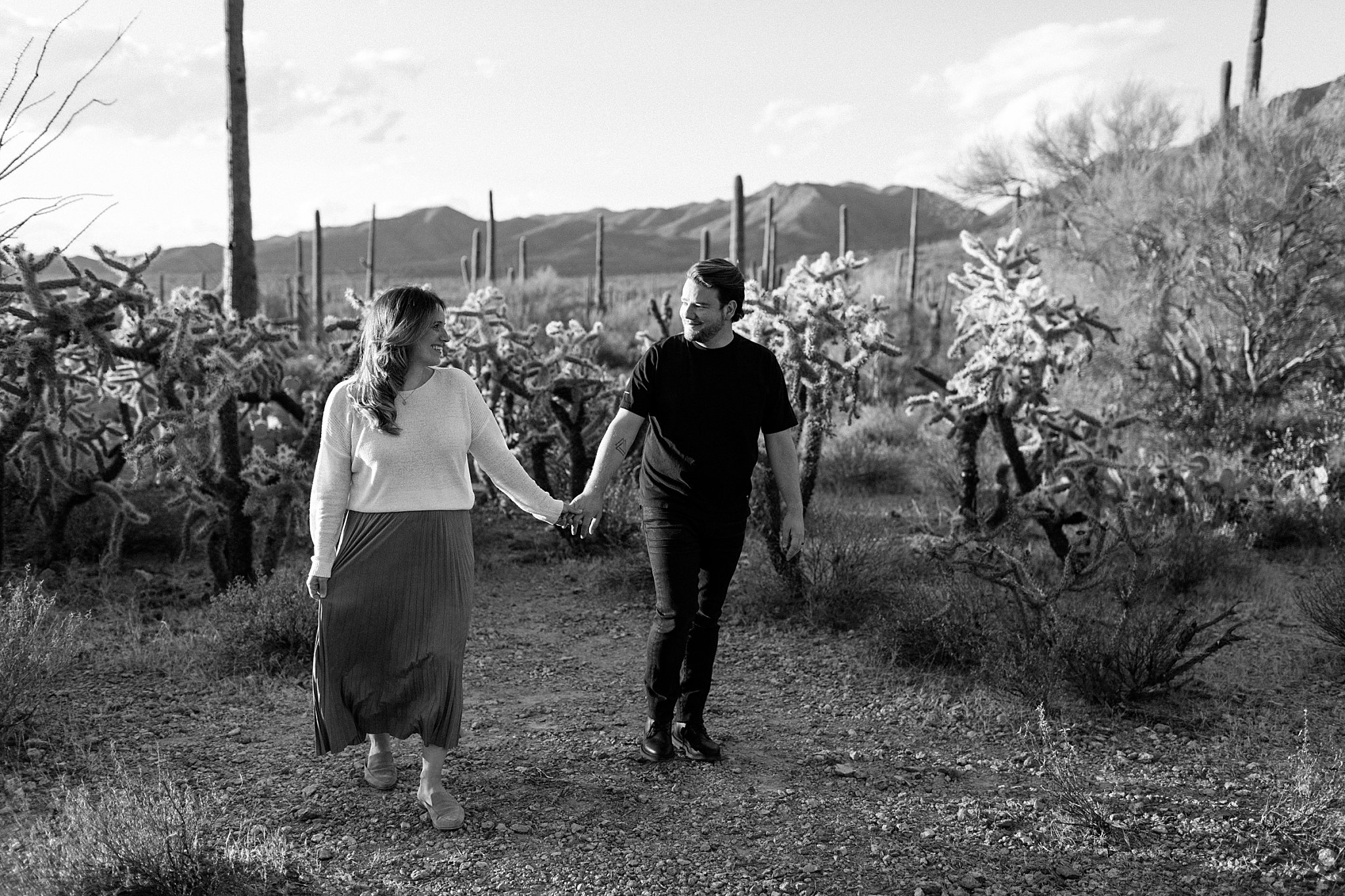  couple looks at each other while holding hands and walking by Arizona Couples Photographer 