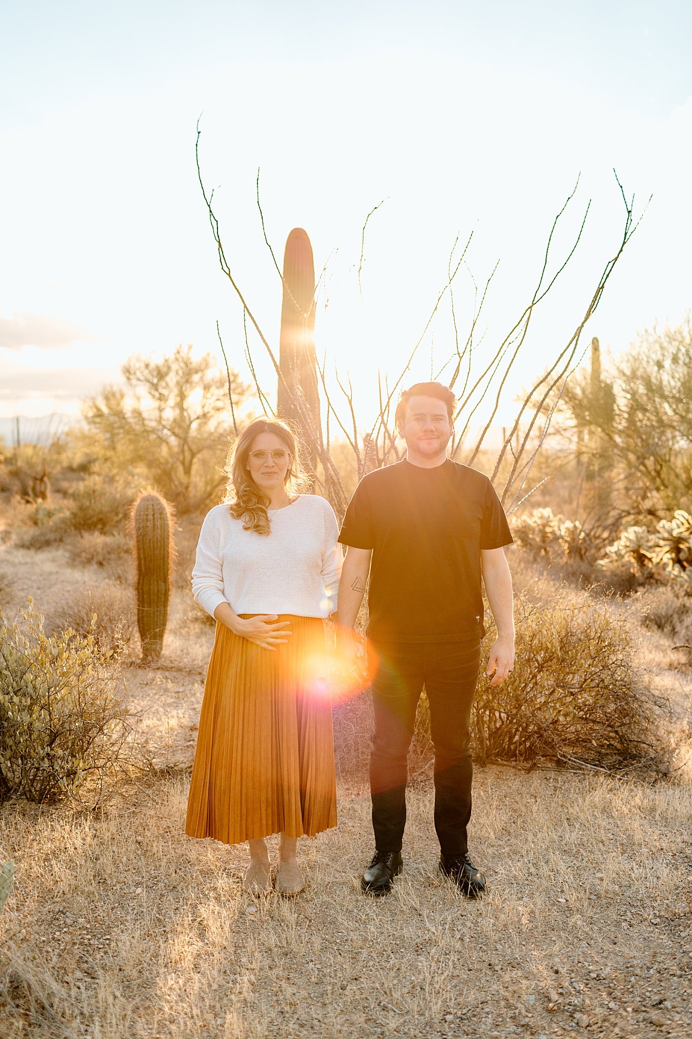  man and woman hold hands in front of sunset in desert by Lucy B Photography 