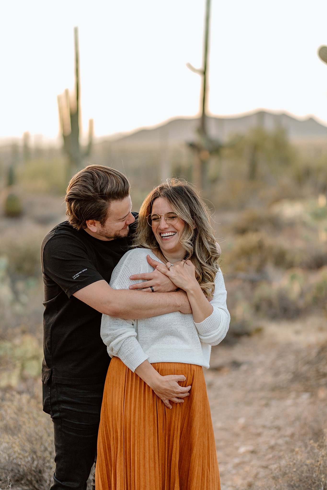  parents-to-be smile while hugging by Arizona Couples Photographer 
