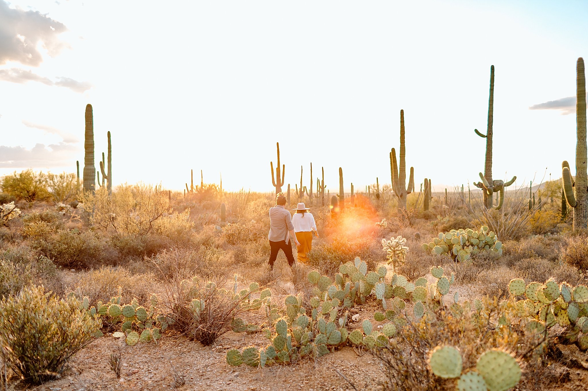  man and woman stand in desert as bright sun shines by Lucy B Photography 