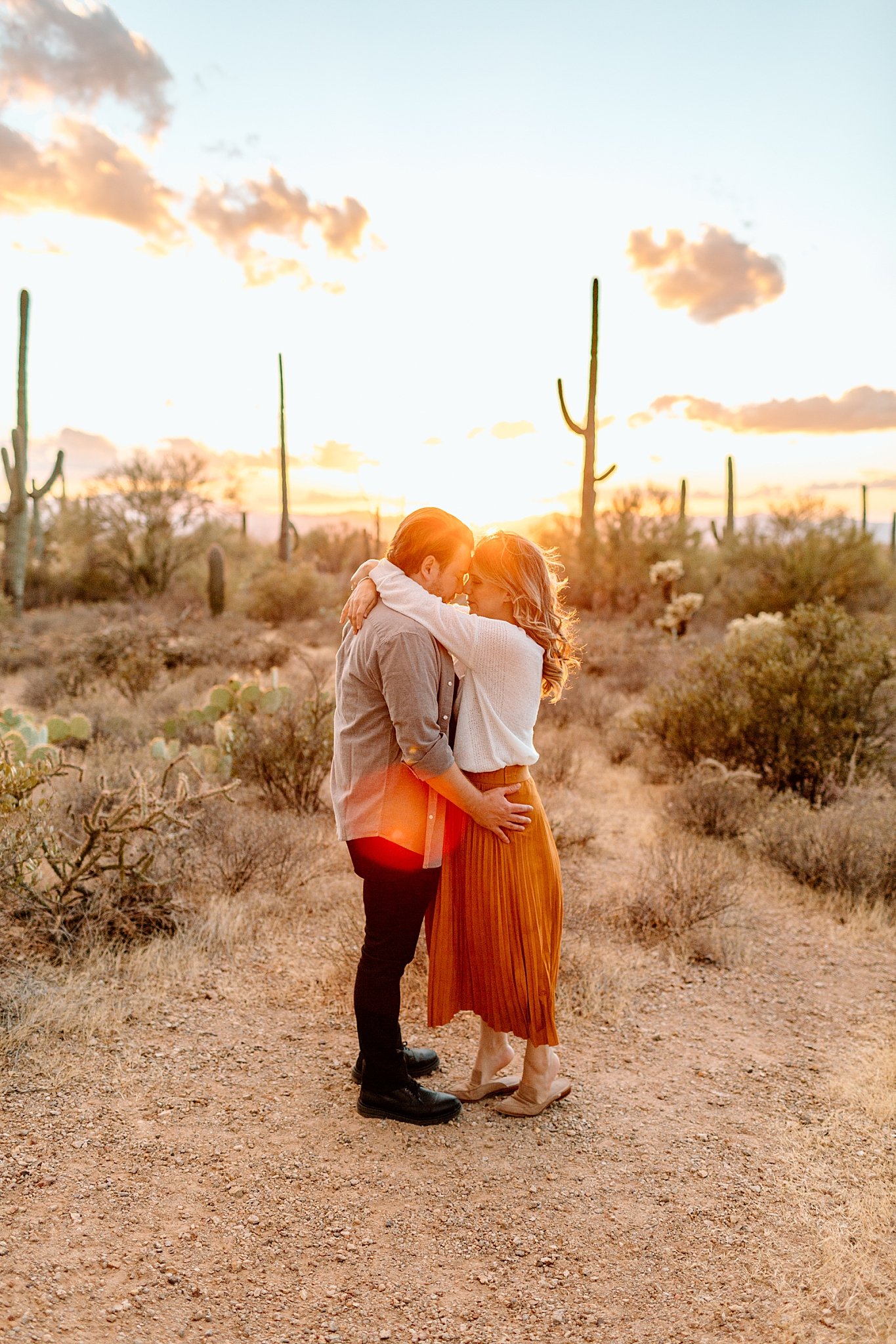  couple embraces and kisses in from of bright shinning sun by Arizona Couples Photographer 