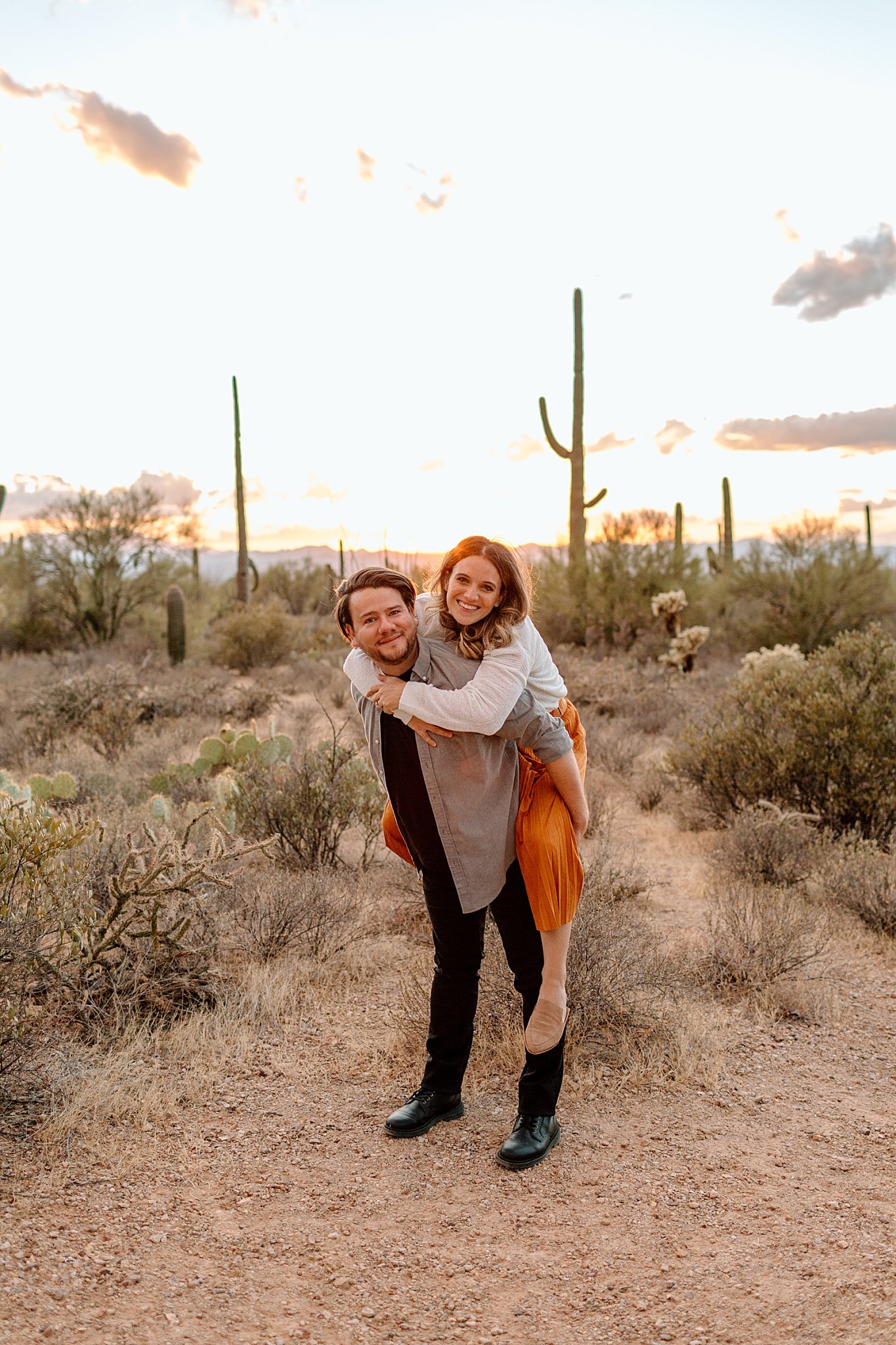  wife rides on husband’s back in desert for Arizona Couples Photographer 