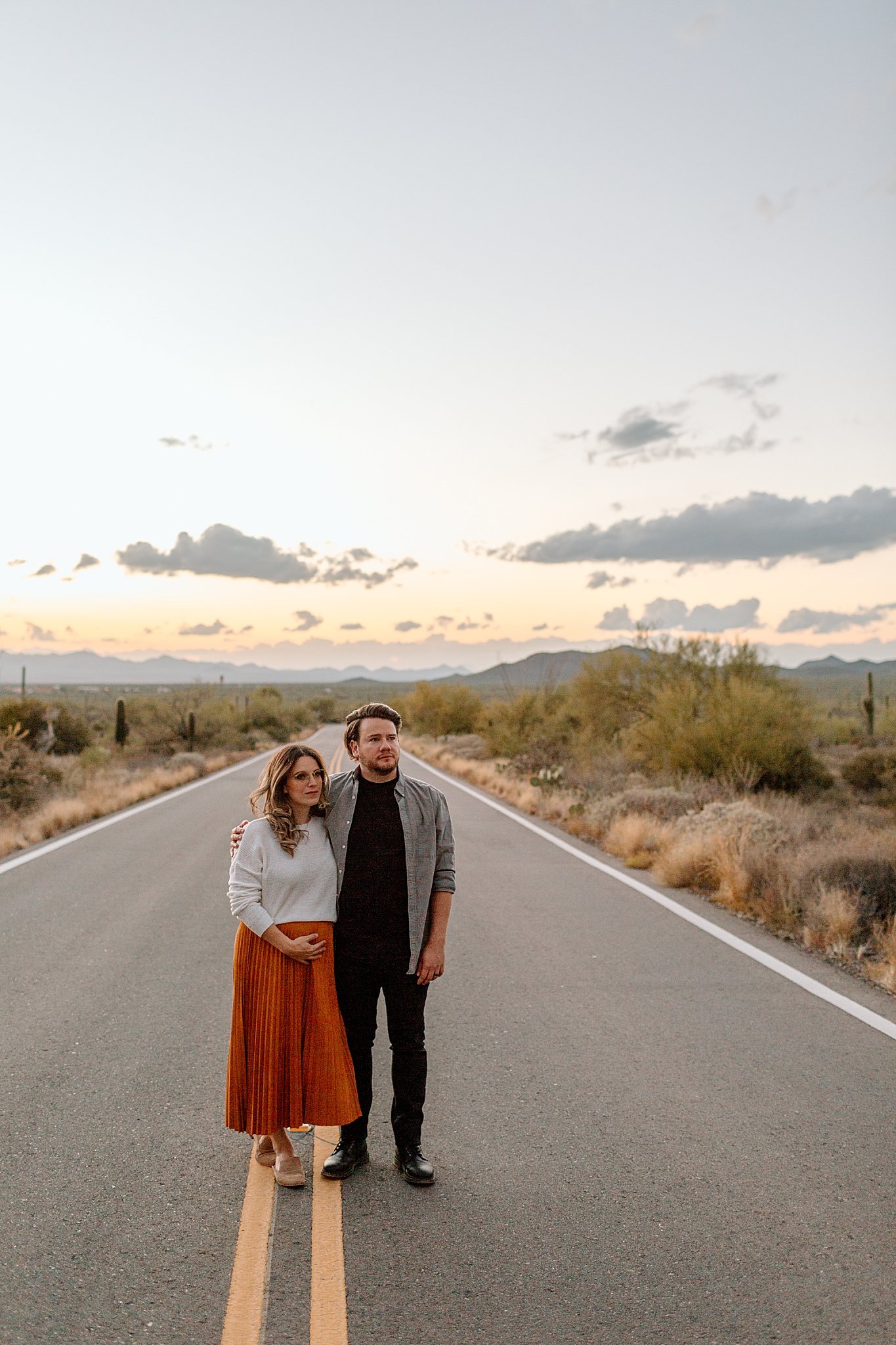  parents-to-be stand in road with sunset behind them by Lucy B Photography 