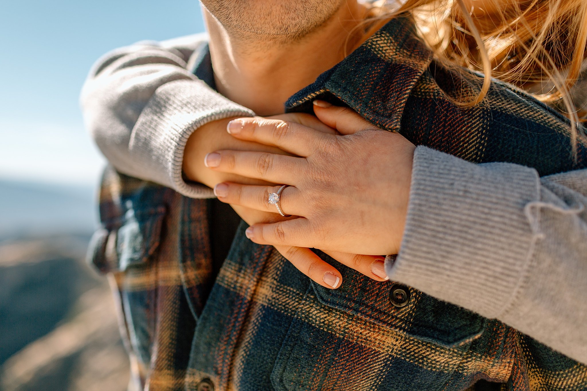  woman hugs man from behind with new ring on finger by Arizona engagement photographer 