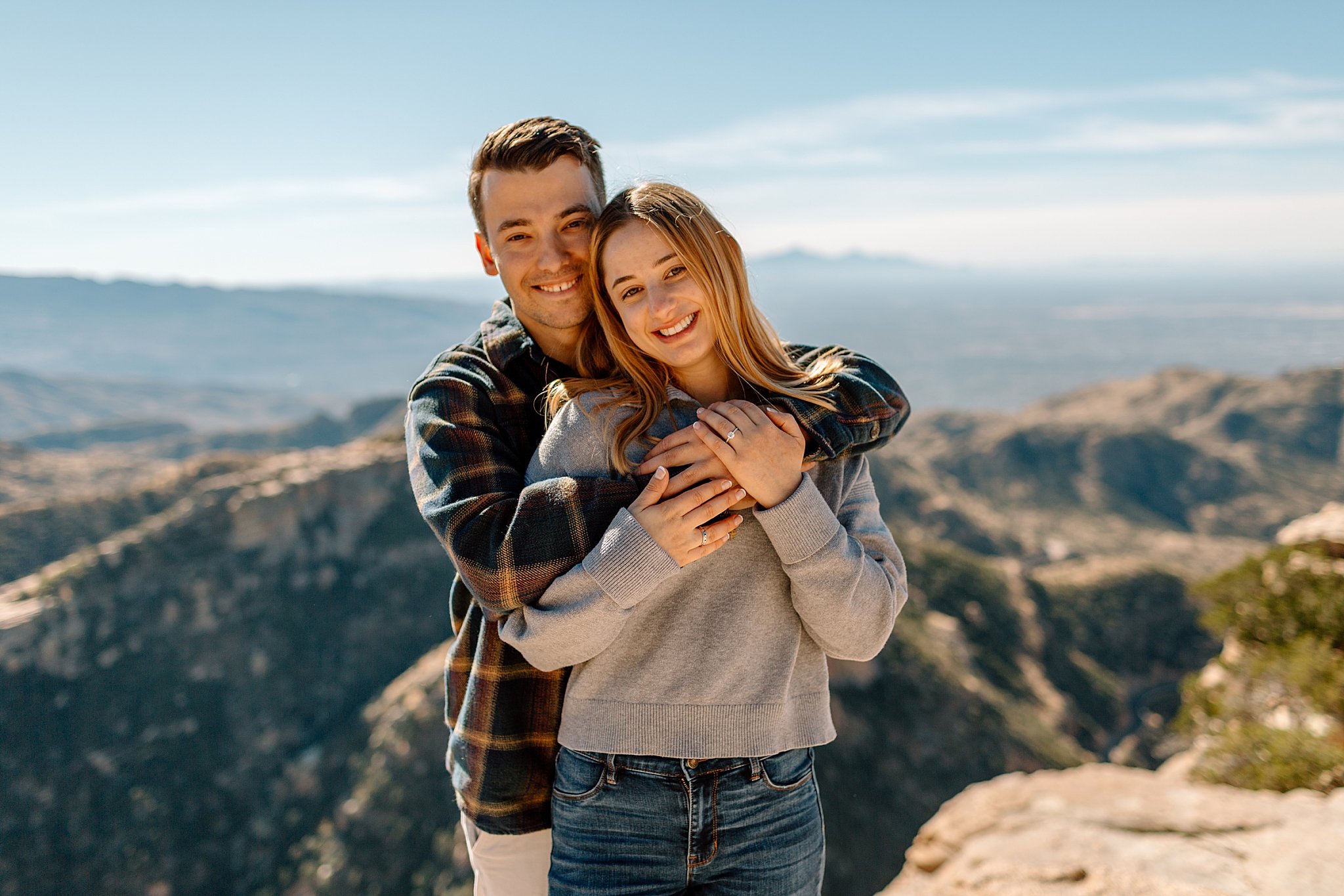  man hugs woman around shoulders from behind at Mount Lemmon proposal 