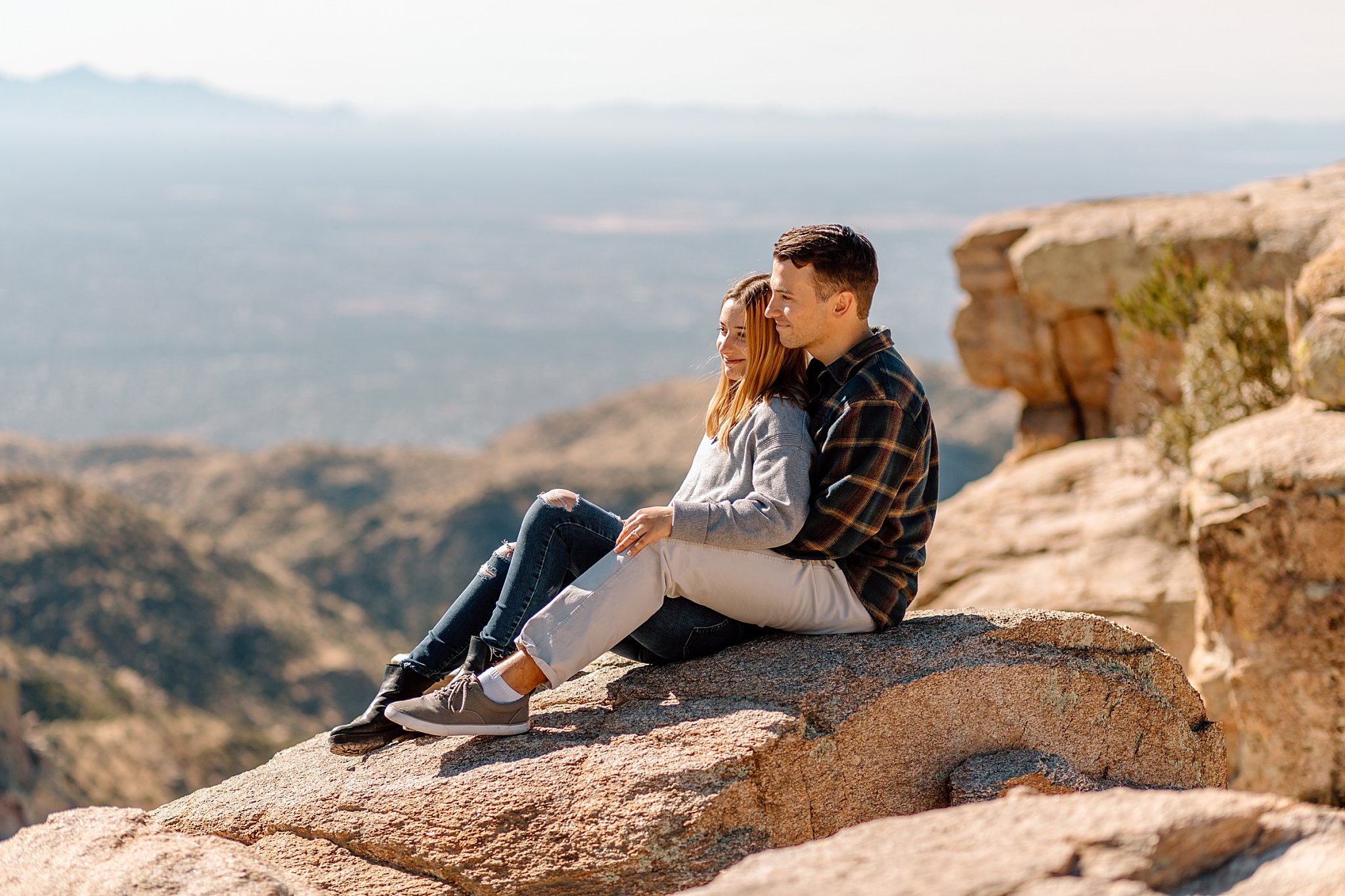  fiances sit leaning on each other on rocks at Windy Point by Lucy B Photography 