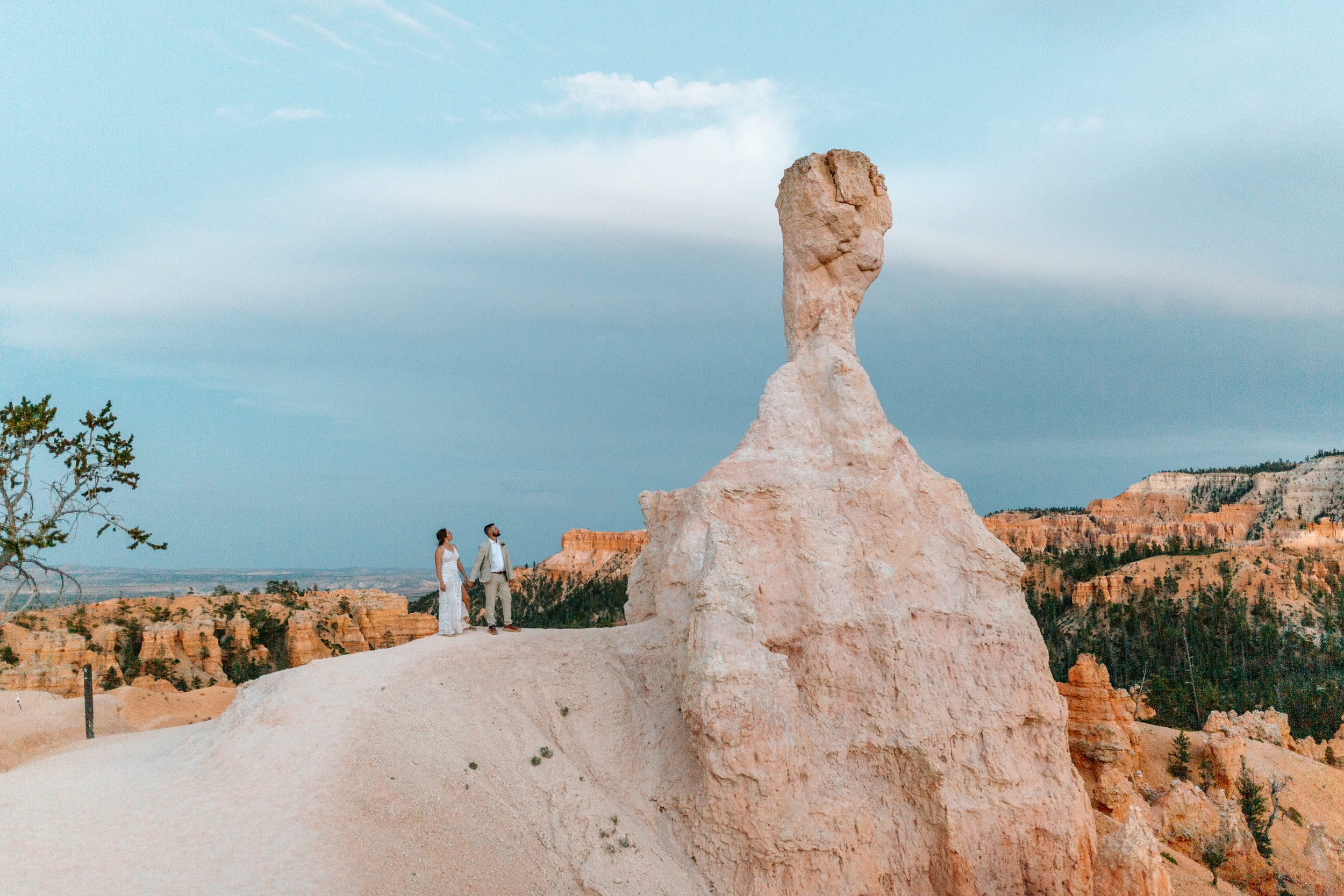  couple looks up at large hoodoo at bryce canyon national park by utah elopement photographer 