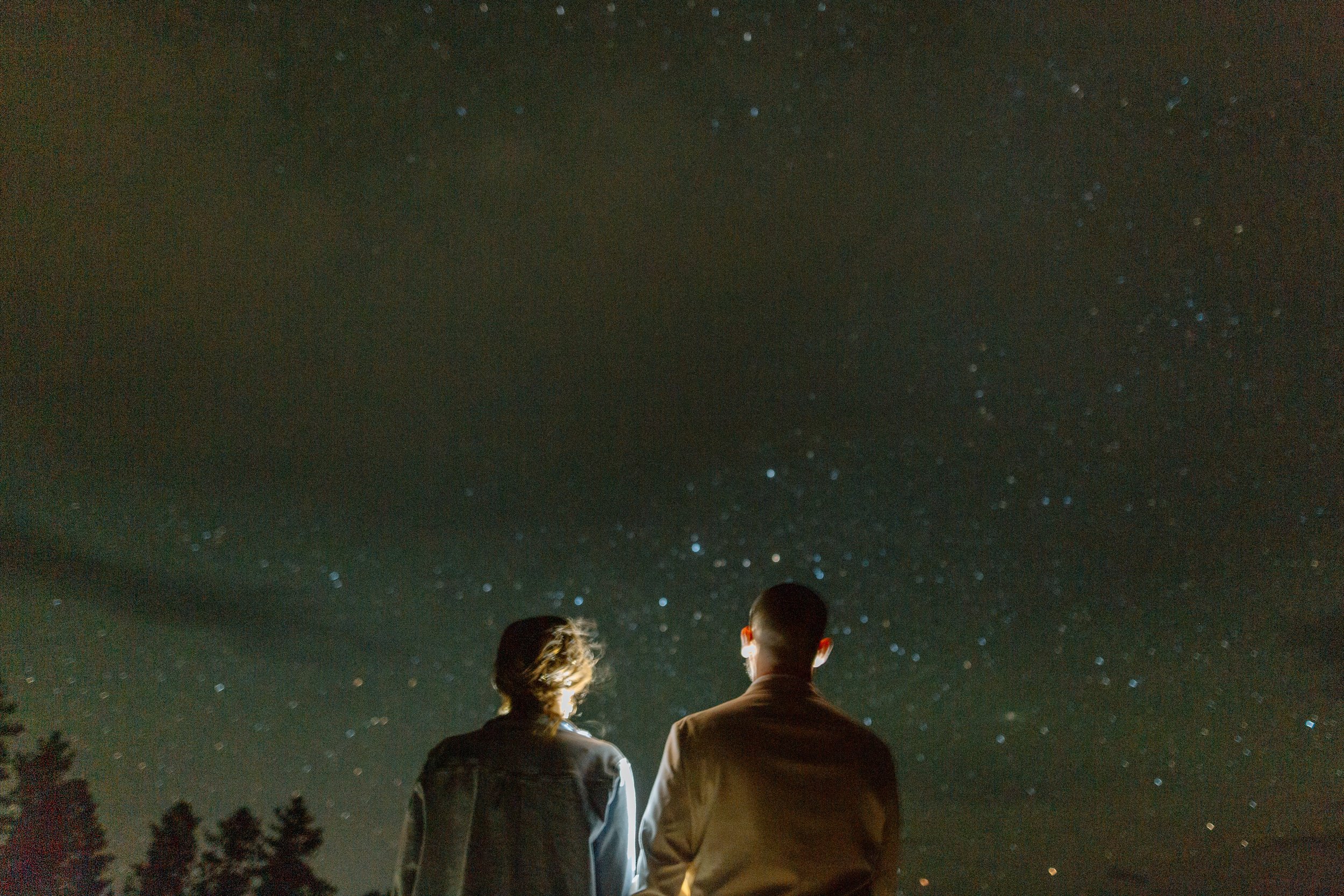  couple looks at night stars while lit from behind during bryce canyon elopement 