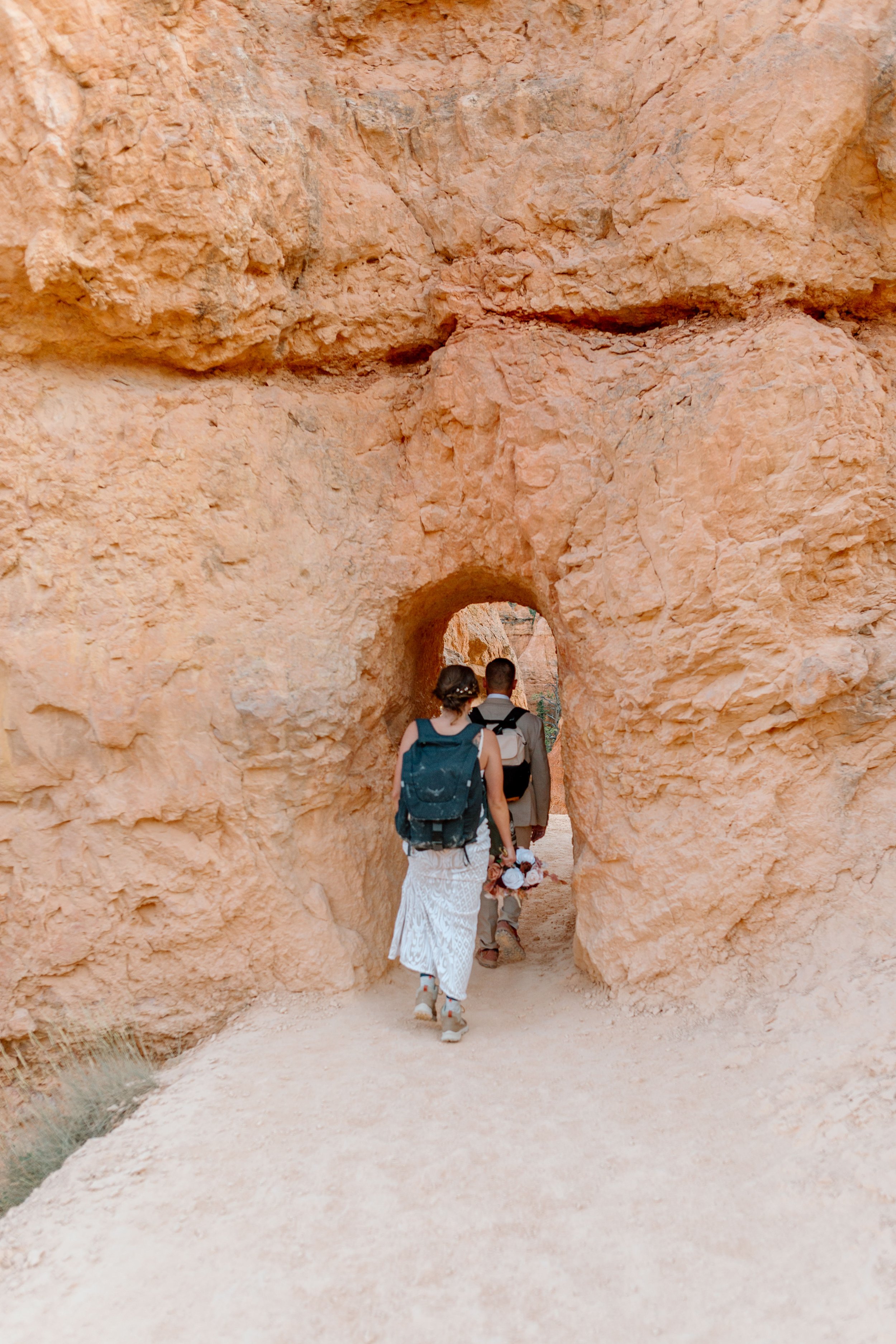  elopement couple hikes under an arch by utah elopement photographer 