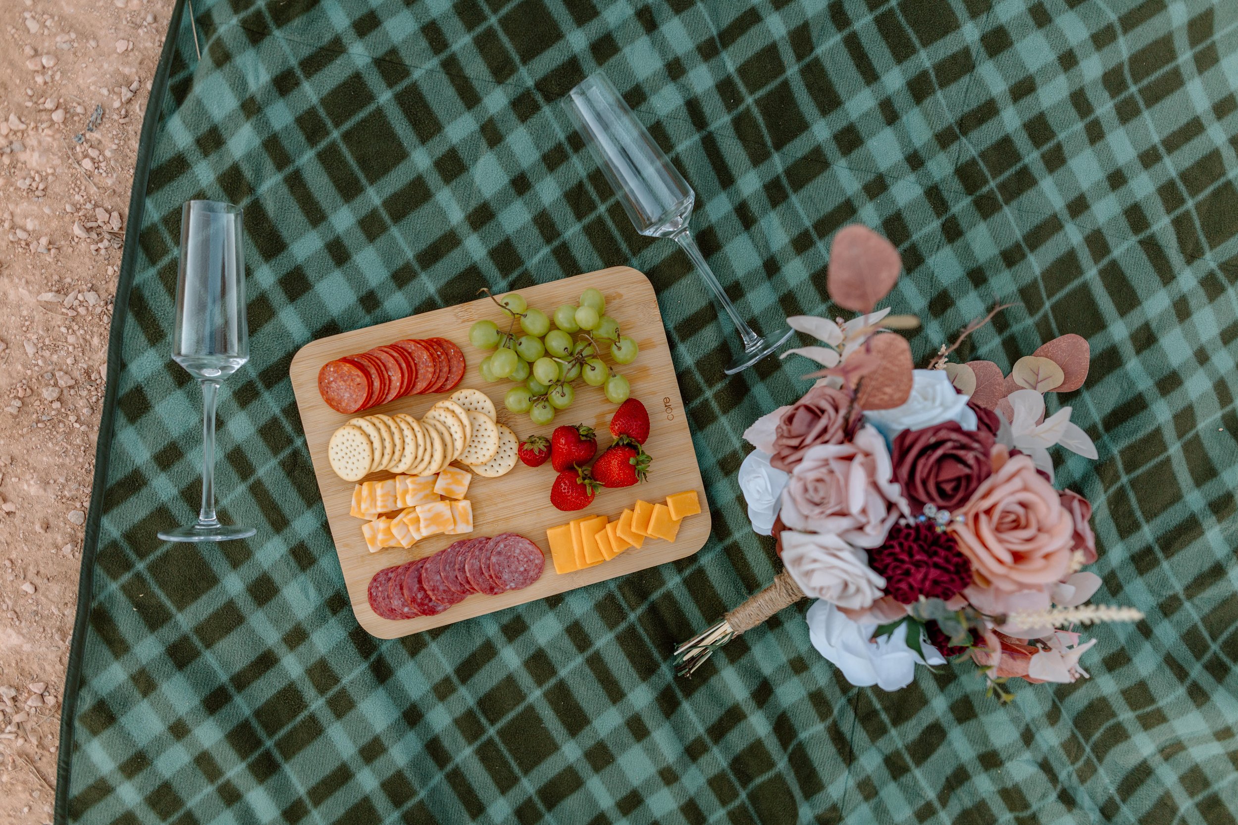  charcuterie board with champagne flutes and flowers on a picnic blanket by utah elopement photographer 
