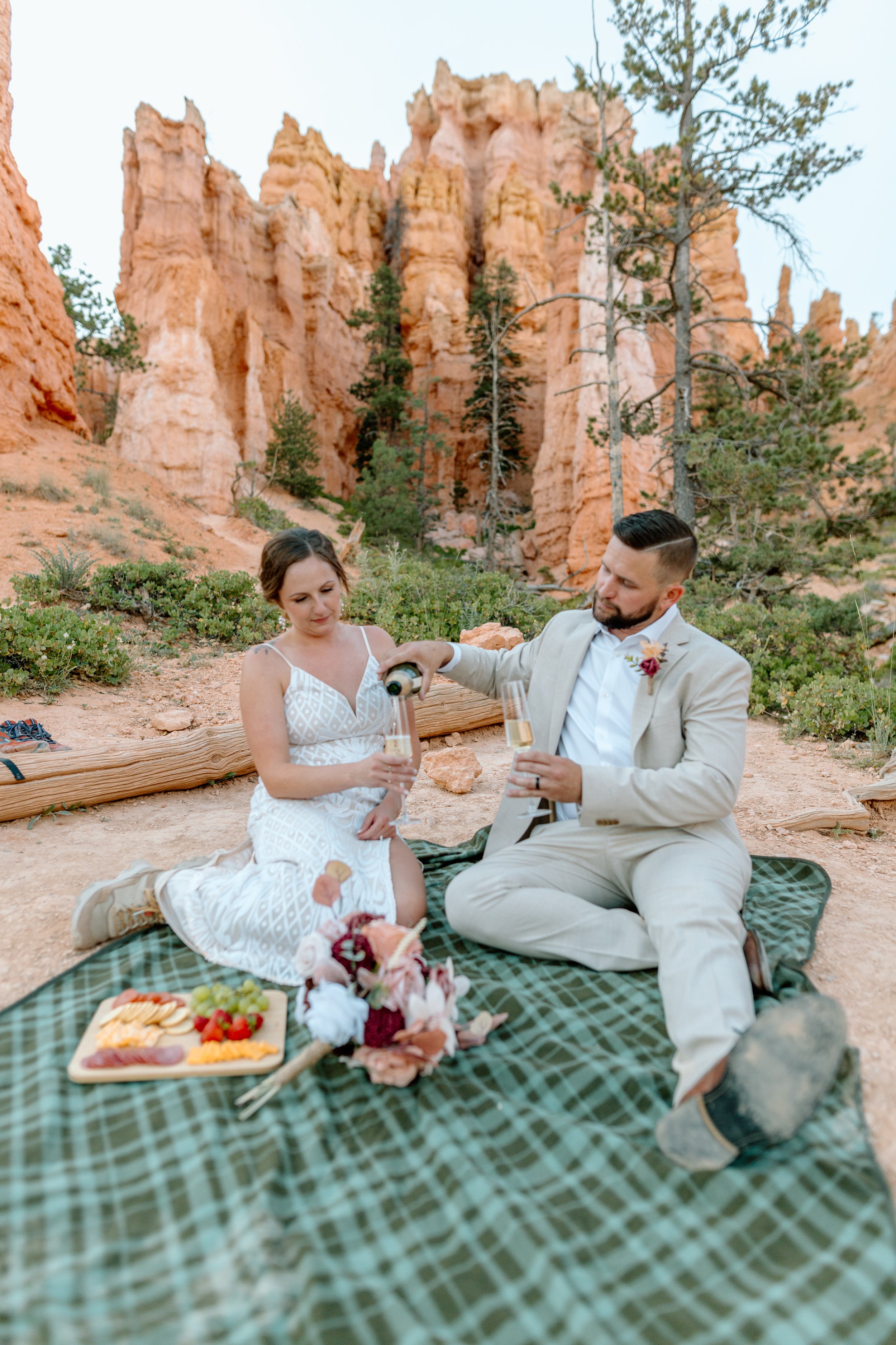  groom pours champagne for bride during their bryce canyon elopement 