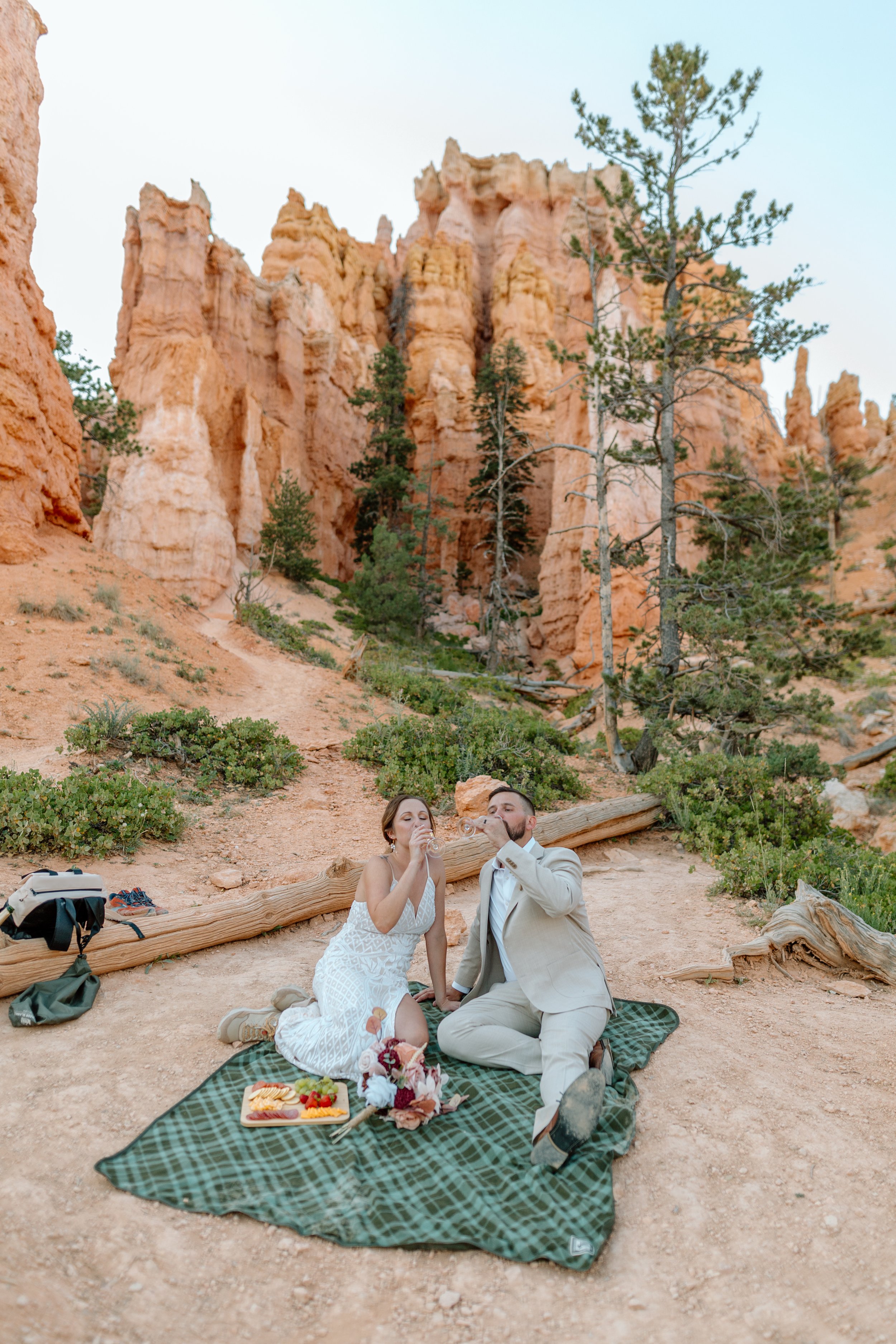  utah elopement couple sips champagne on picnic blanket at bryce canyon national park 