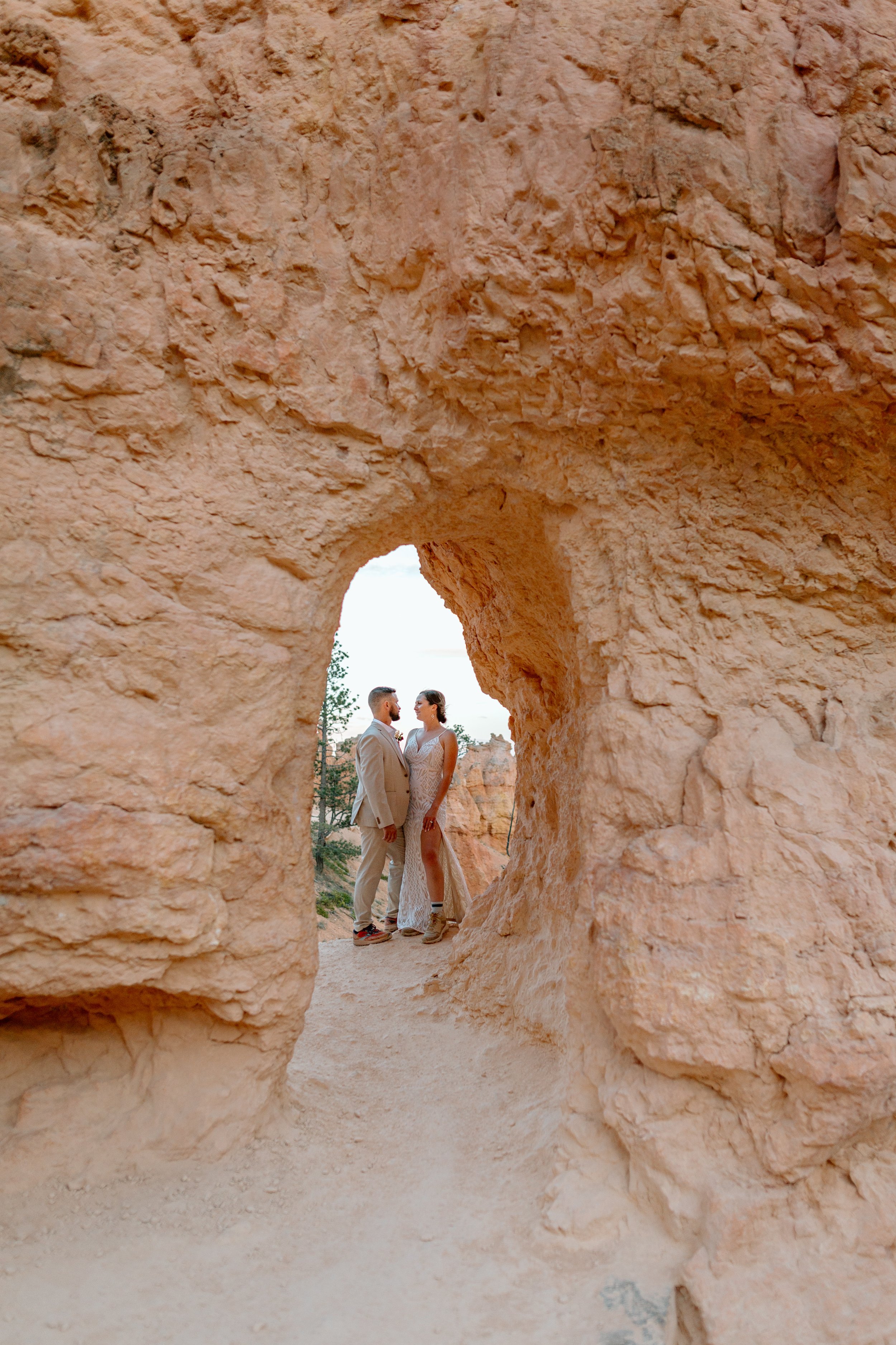  couple looks at each other framed by arch by utah elopement photographer 