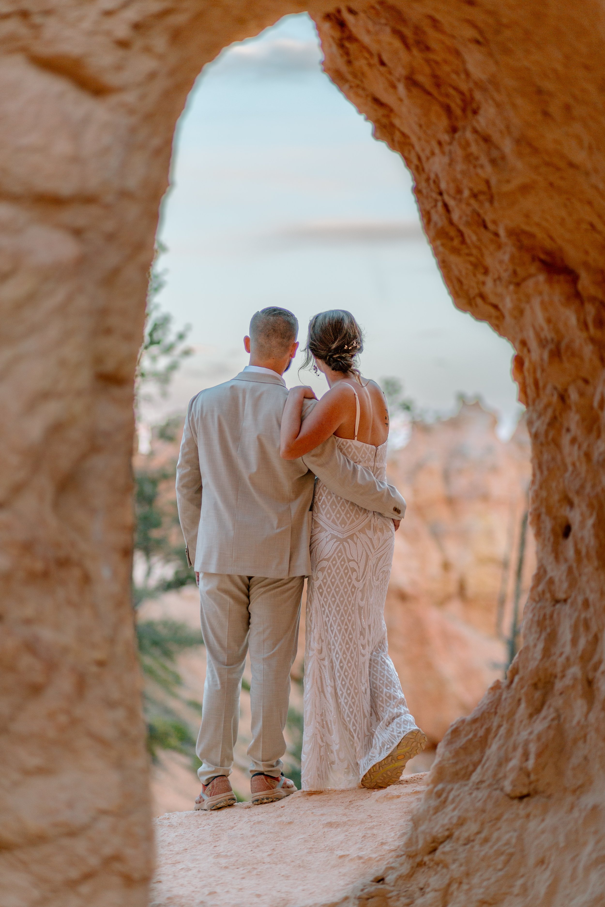  utah elopement couple stares into the distance while framed by arch at bryce canyon national park 