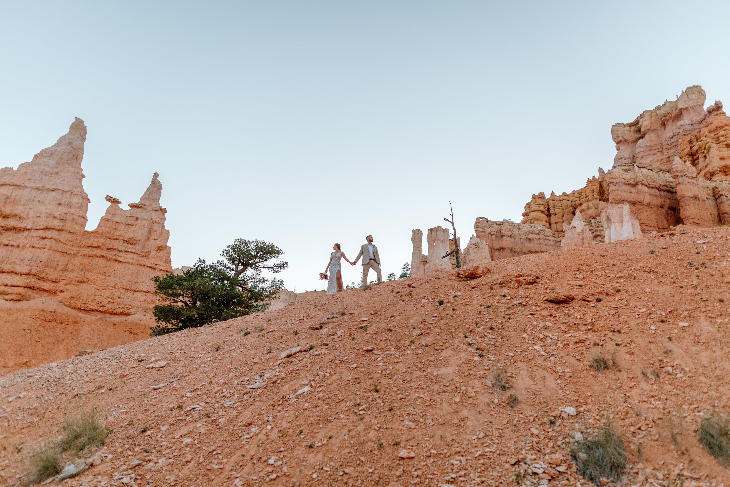  couple holds hands on top of a hill at bryce canyon national park by utah elopement photographer 