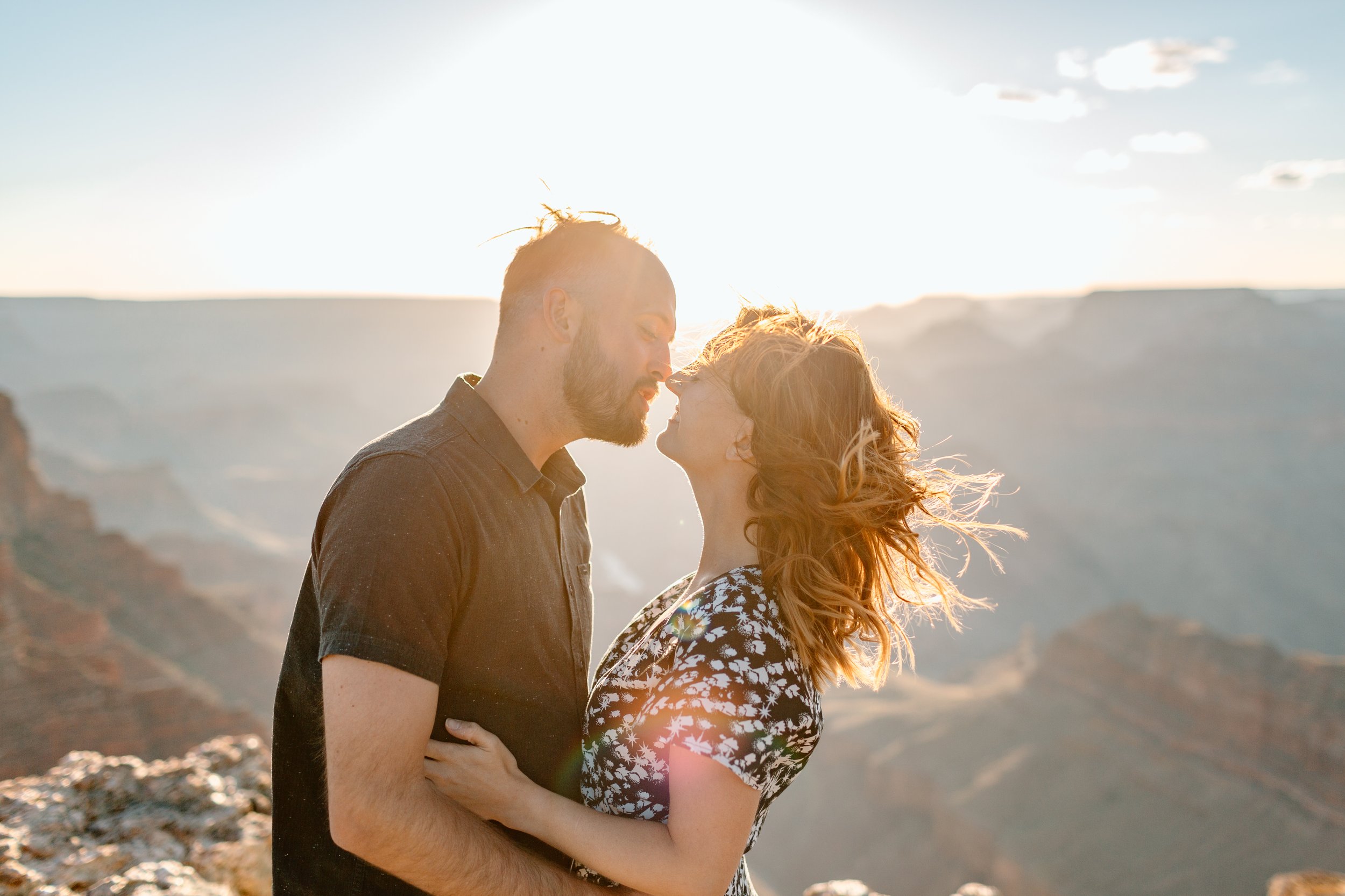  couple goes in for a kiss in front of a grand canyon sunset 