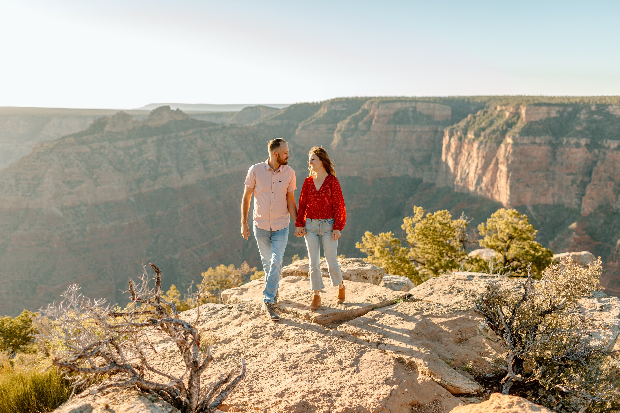  couple holds hands and walks together for their grand canyon engagement session 