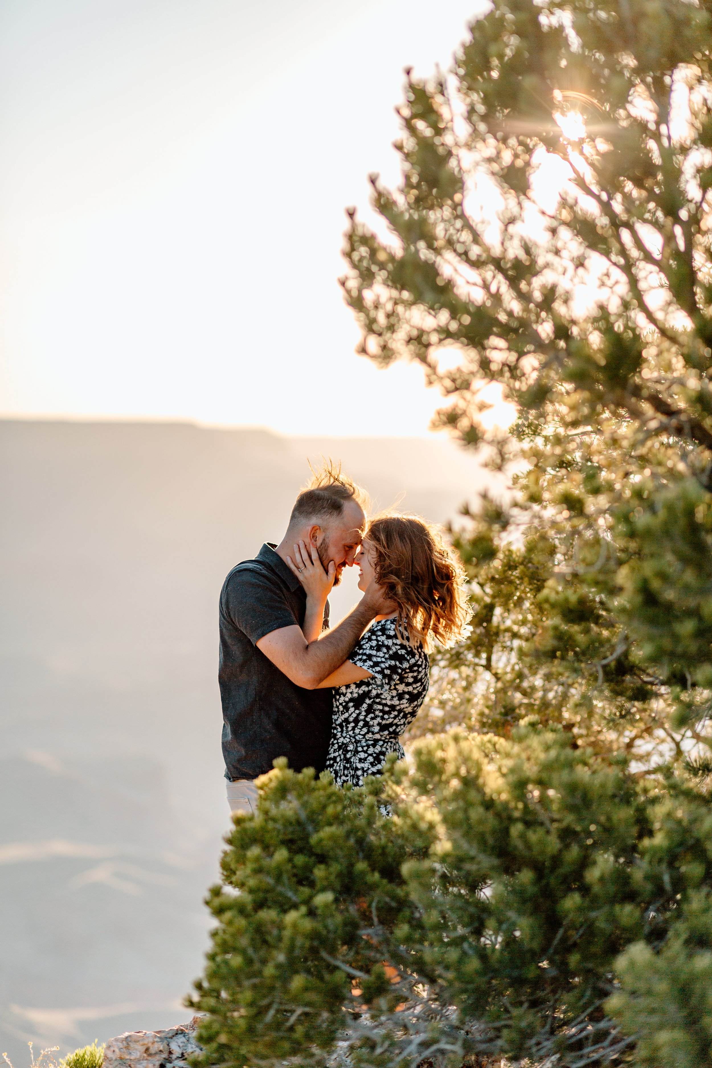  couple holds each other as sun shines through the trees during their grand canyon engagement session 