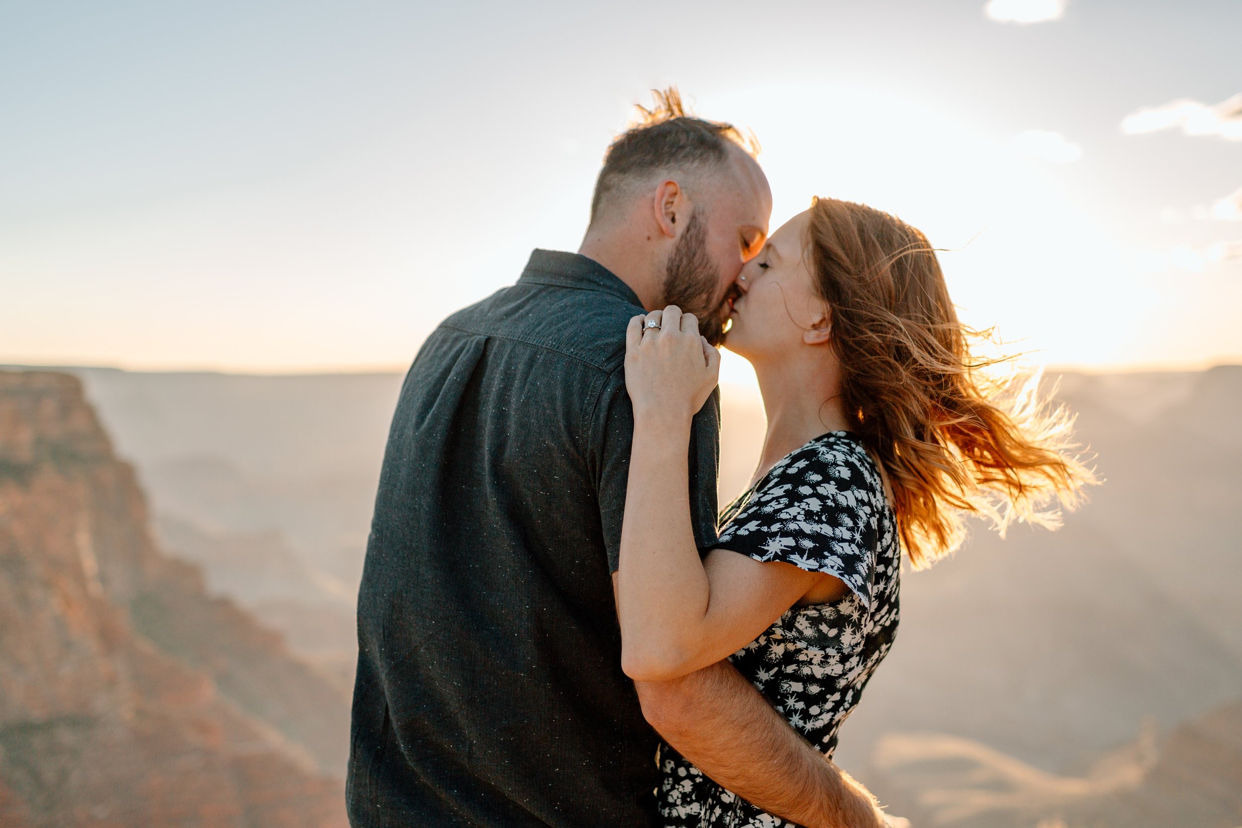  couple kisses with windblown hair in front of a grand canyon sunset 