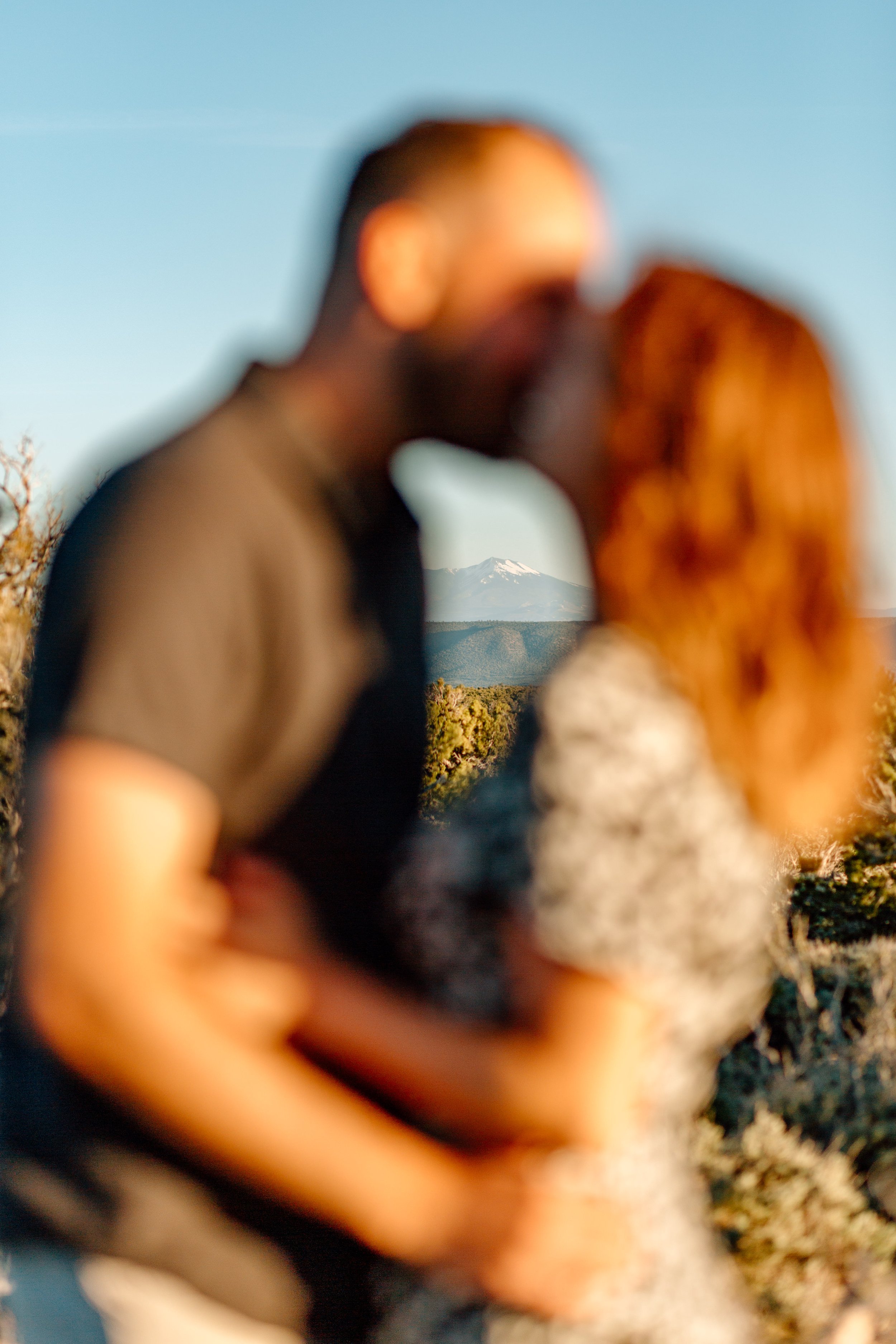  blurry couple kisses with mount humphreys in focus in the background 